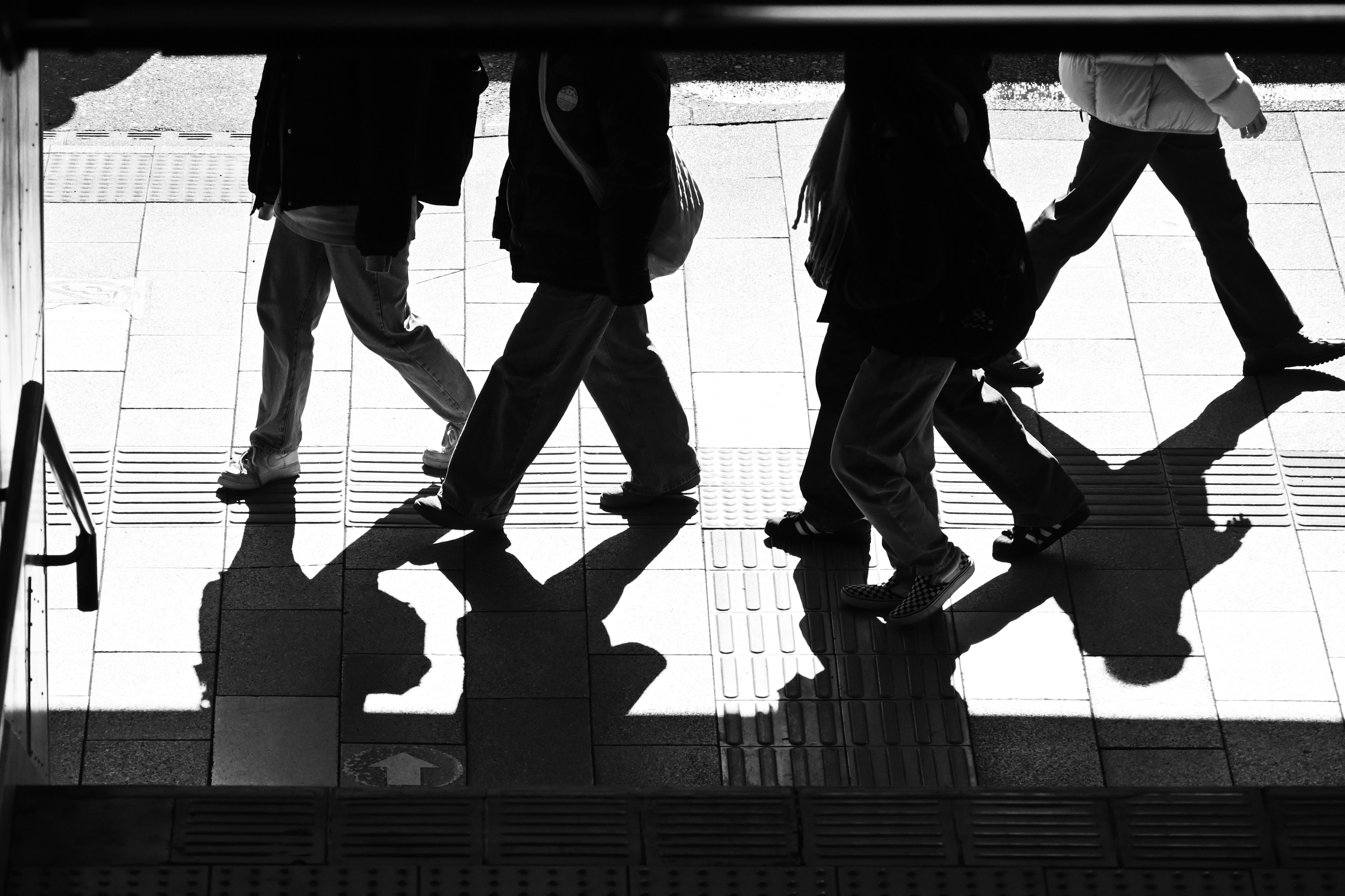 Silhouettes of people walking reflected on a surface in black and white