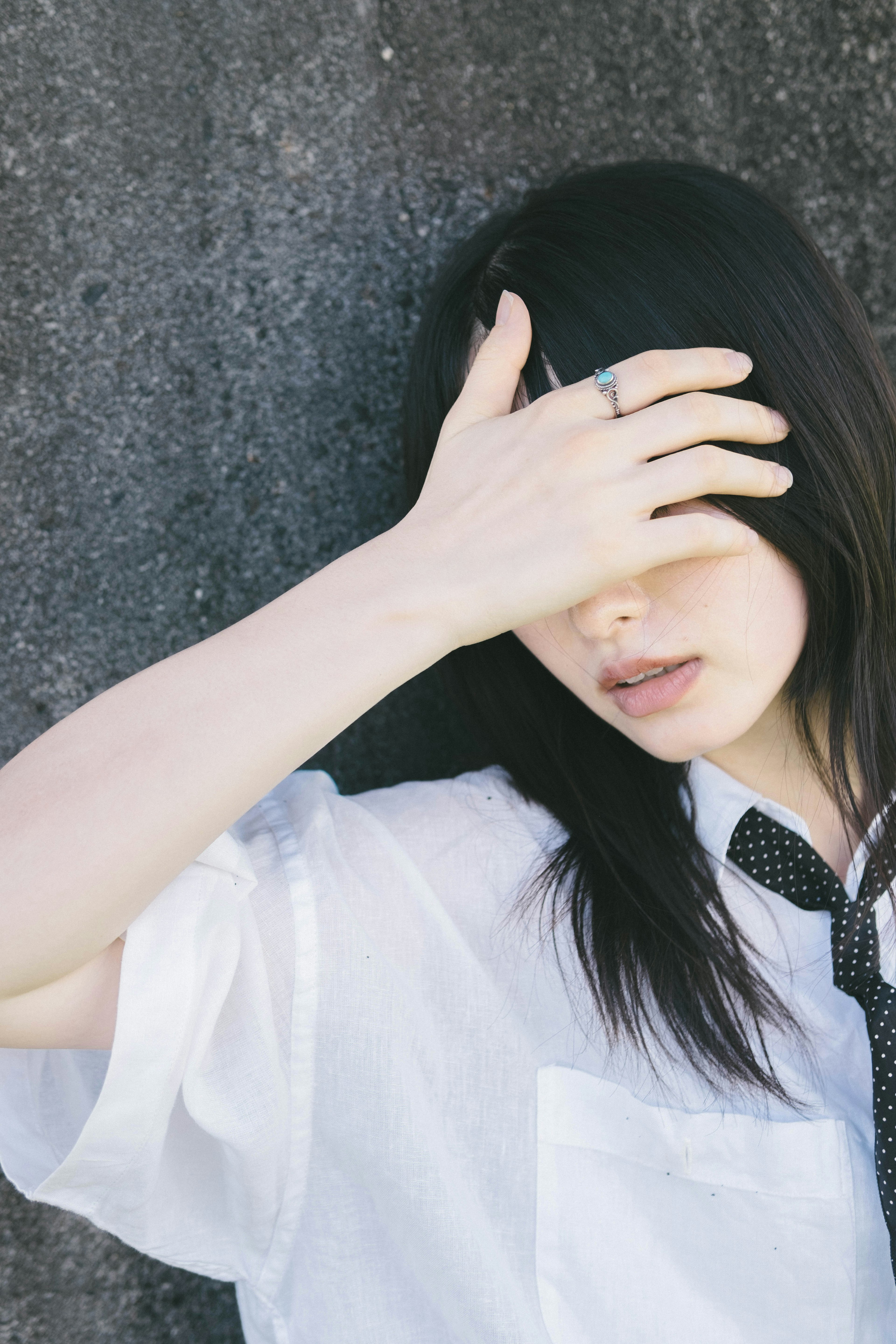 Stylish portrait of a woman leaning against a wall covering her face with her hand