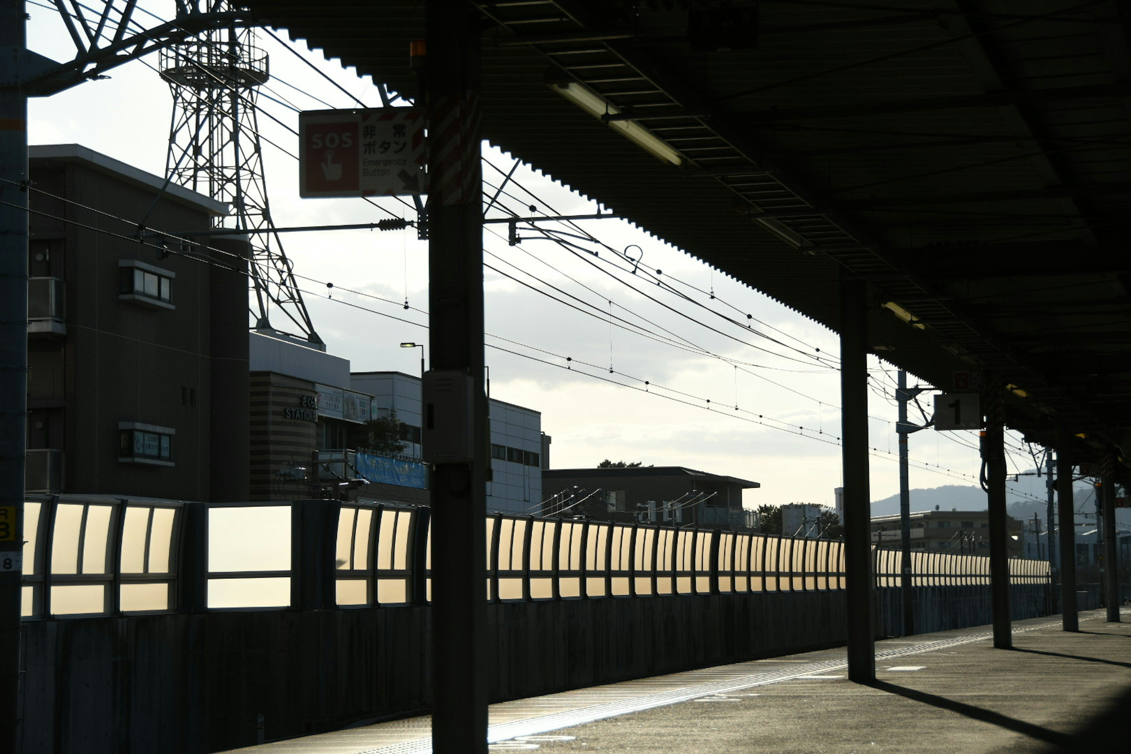 Silhouette of a train station platform with buildings in the background