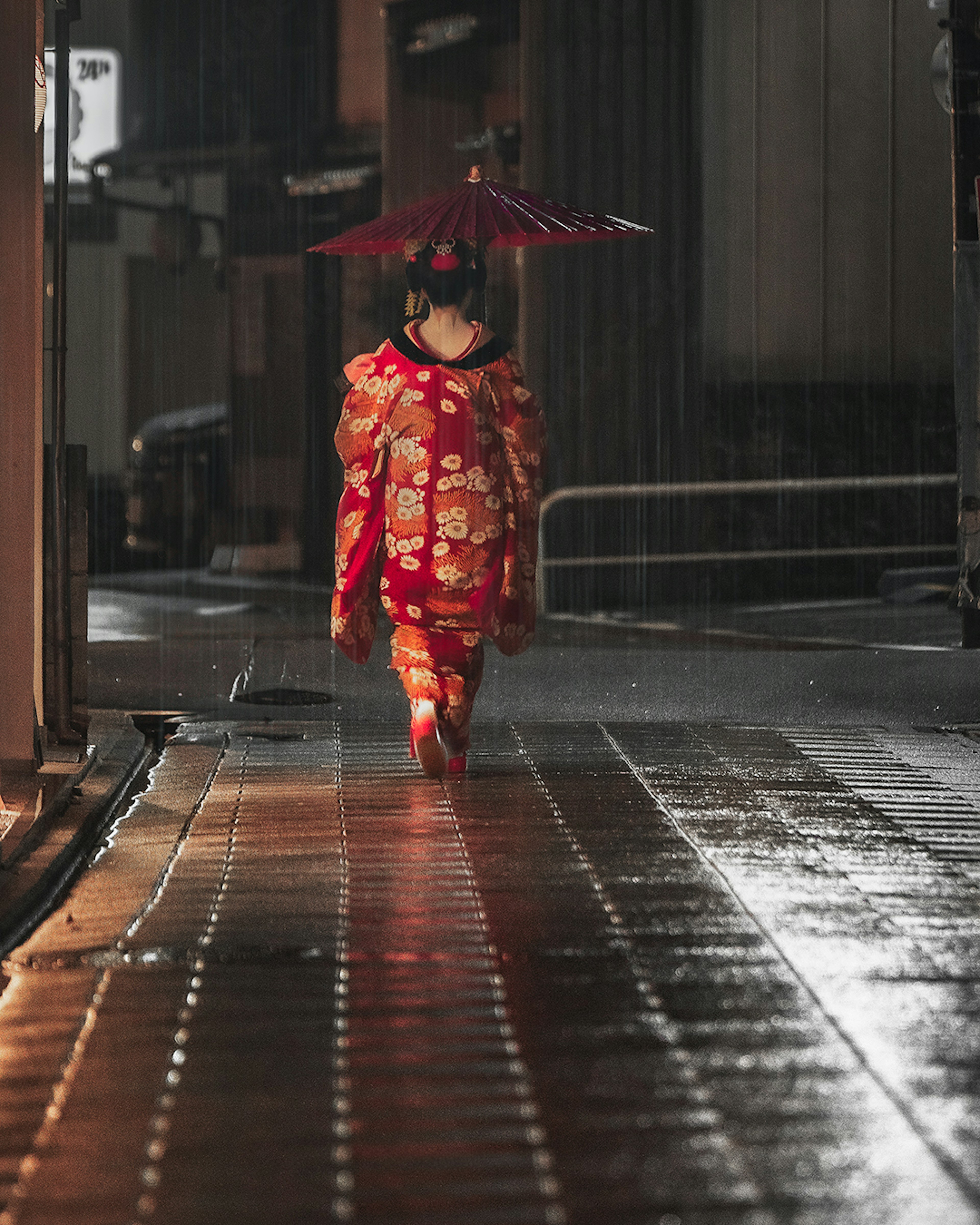 雨の中、赤い着物を着た女性が傘を持って歩いている