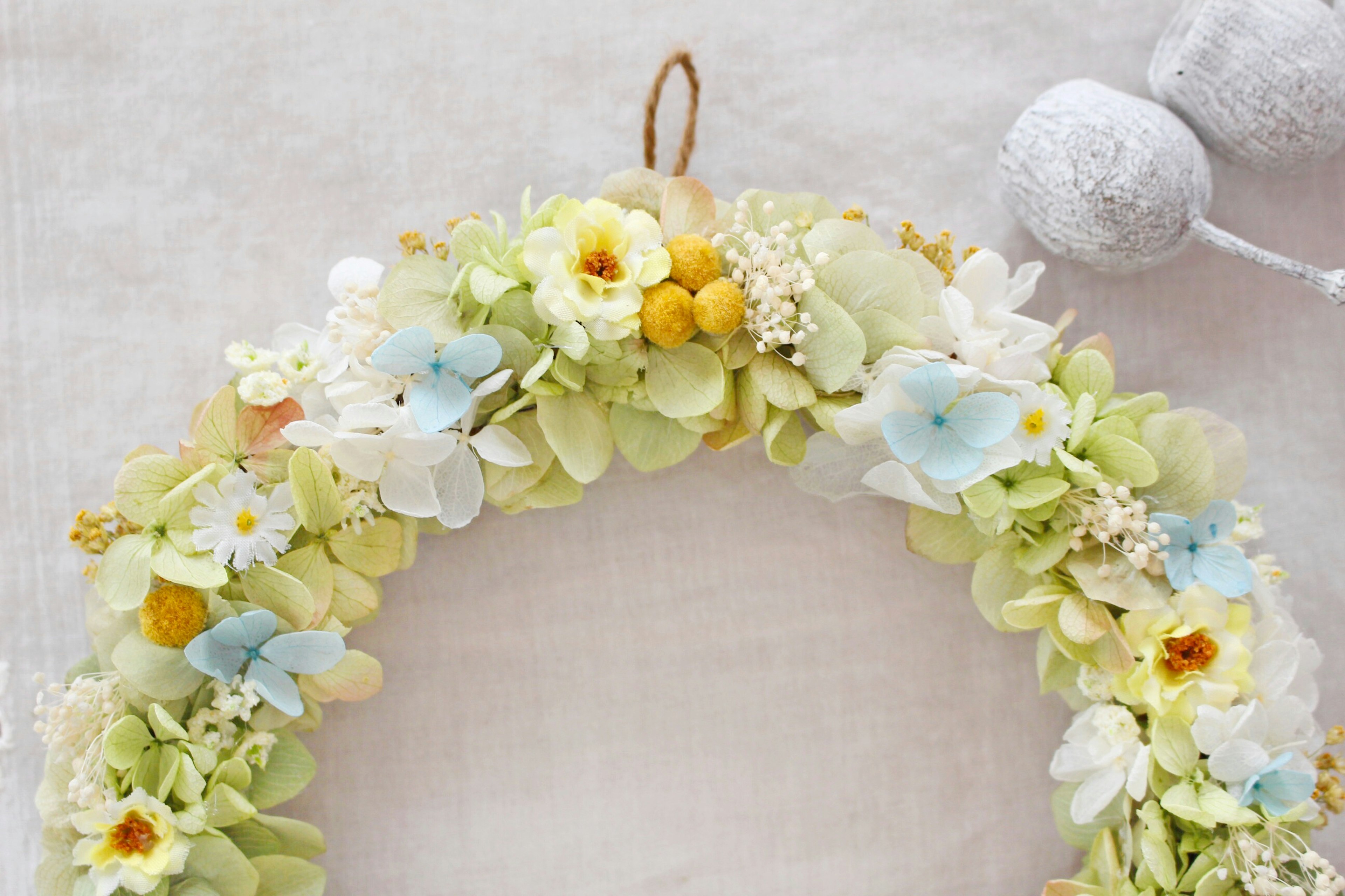 A floral wreath adorned with pastel-colored flowers and white decorations