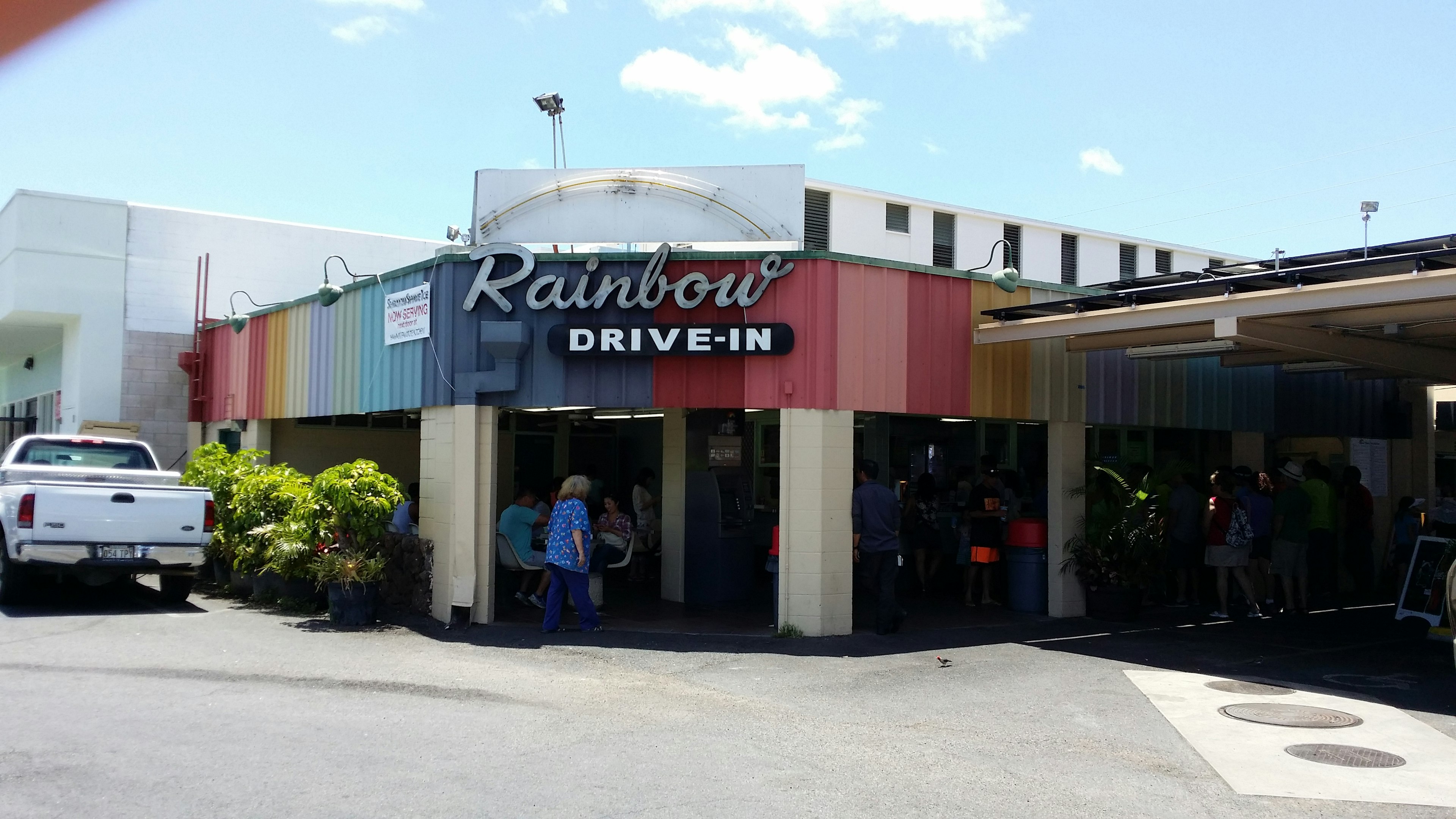 Rainbow Drive-In dengan eksterior berwarna-warni dan orang-orang berkumpul di luar