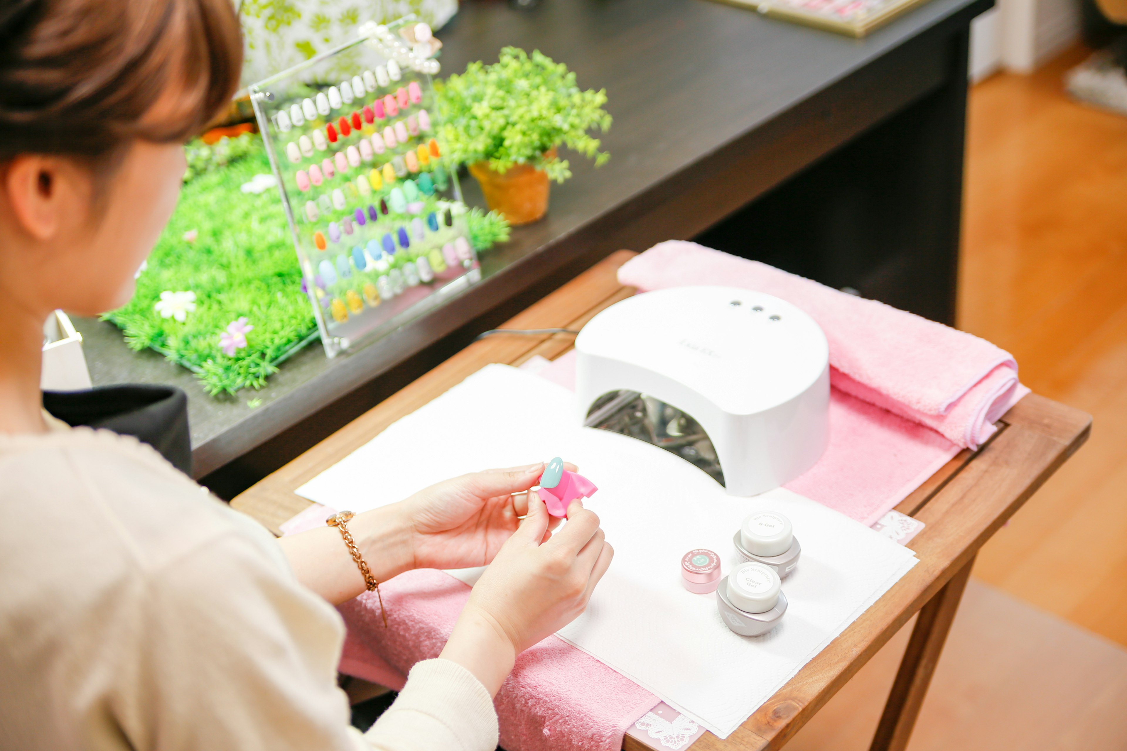 Seorang wanita yang menikmati seni kuku memilih cat kuku di atas handuk pink