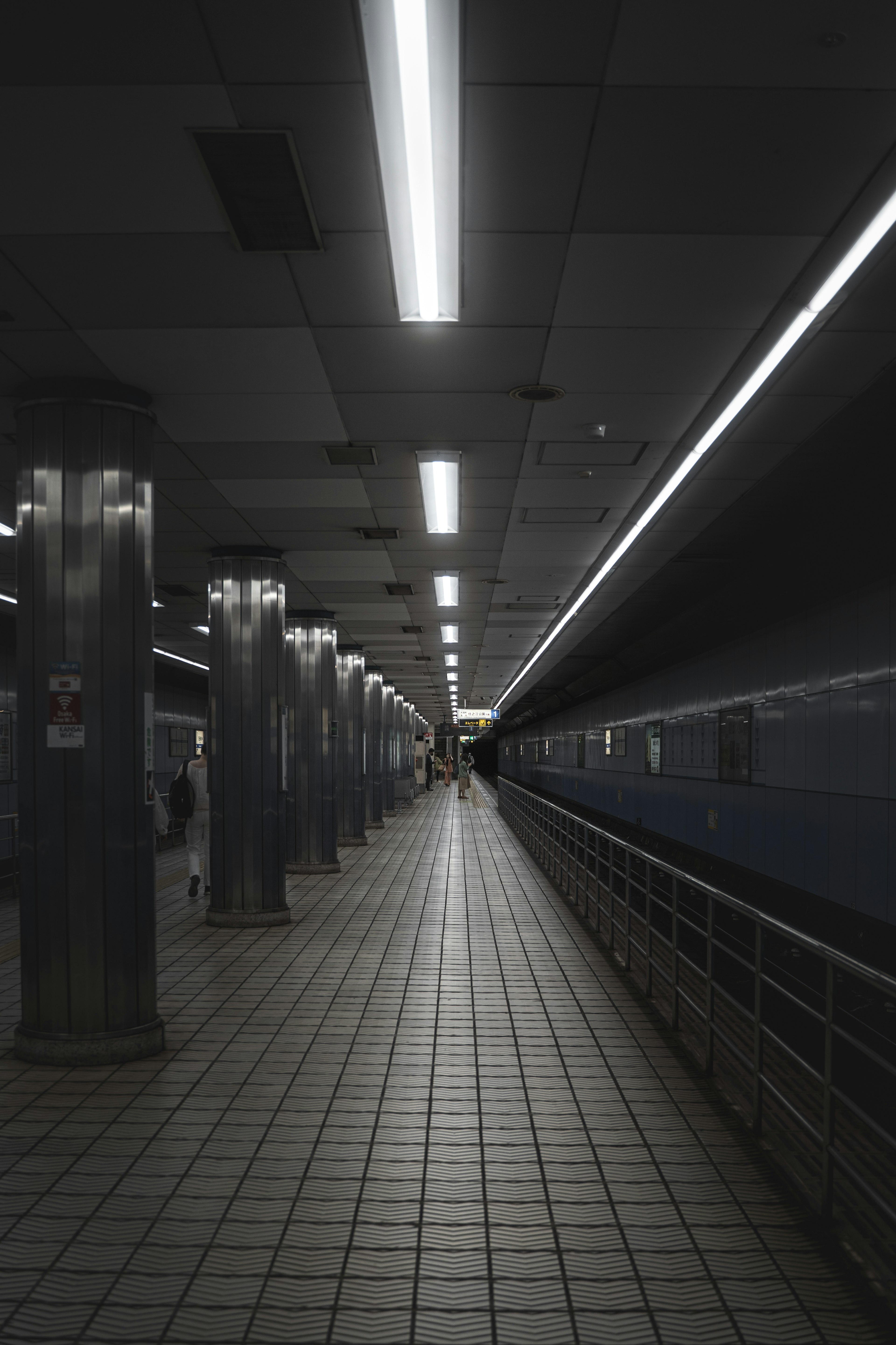 Corridoio di stazione della metropolitana scuro con illuminazione e pavimento piastrellato