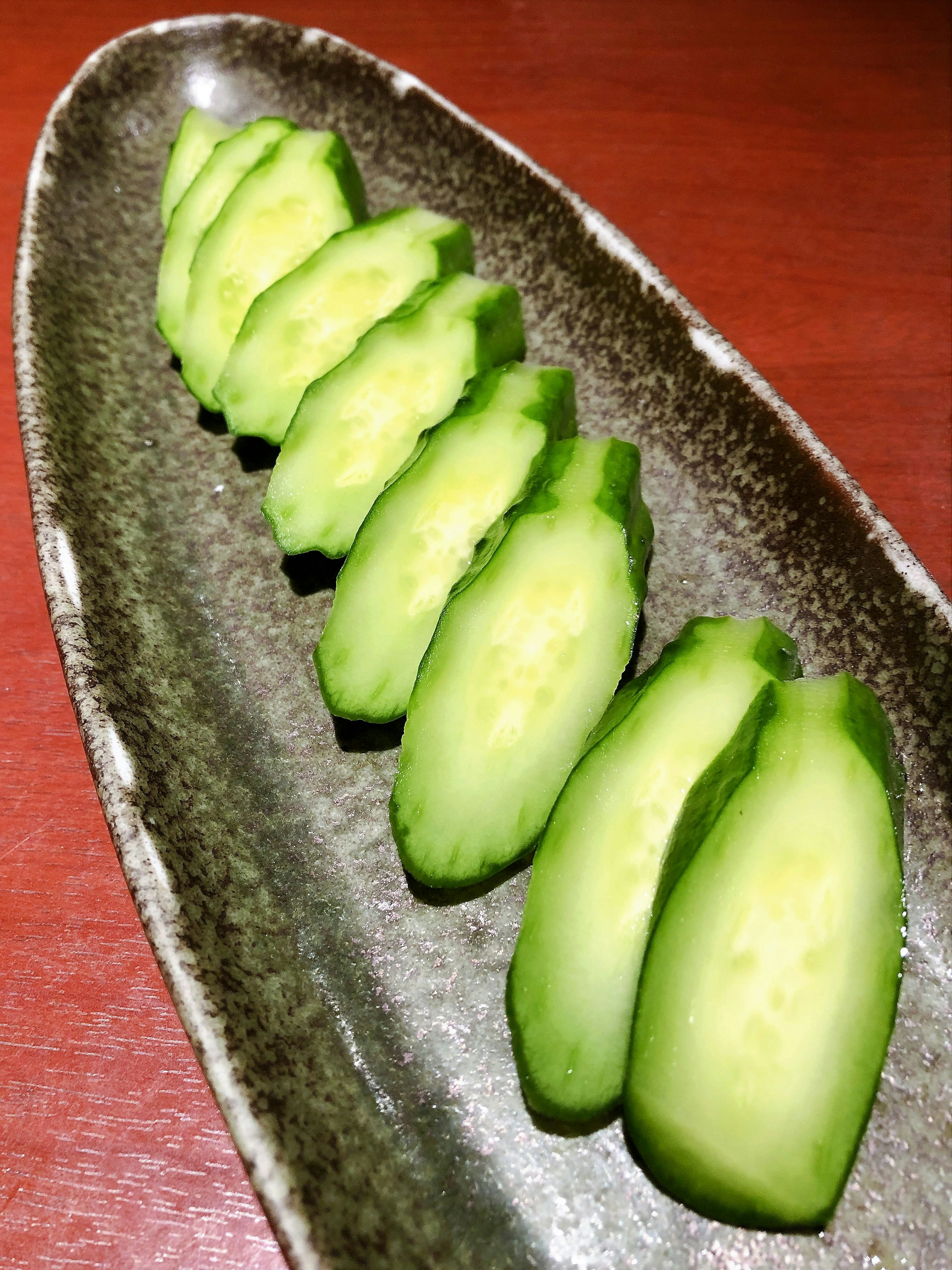 Fette di cetriolo verde disposte su un piatto scuro