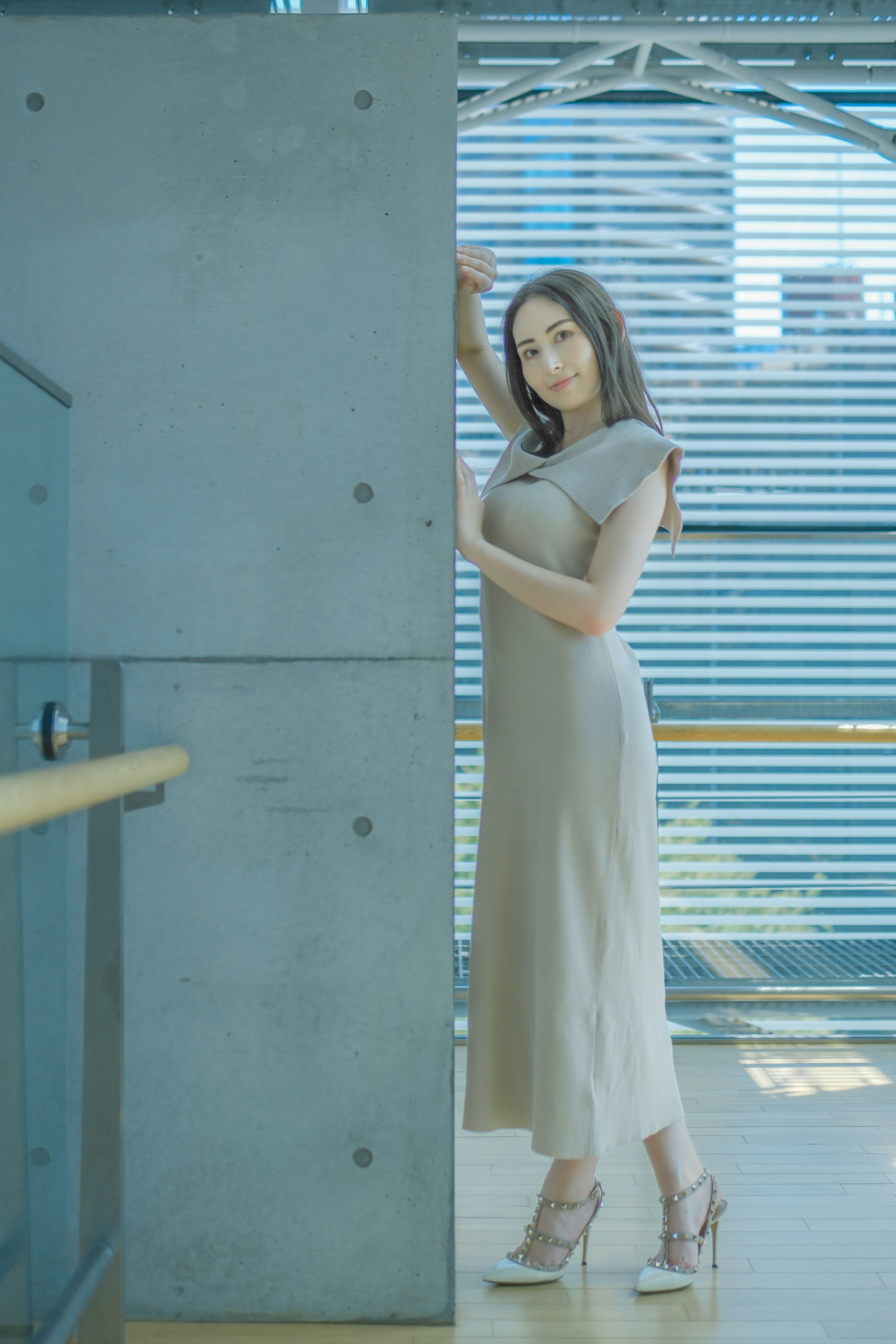 Eine Frau, die in einem eleganten Kleid an einer grauen Wand posiert