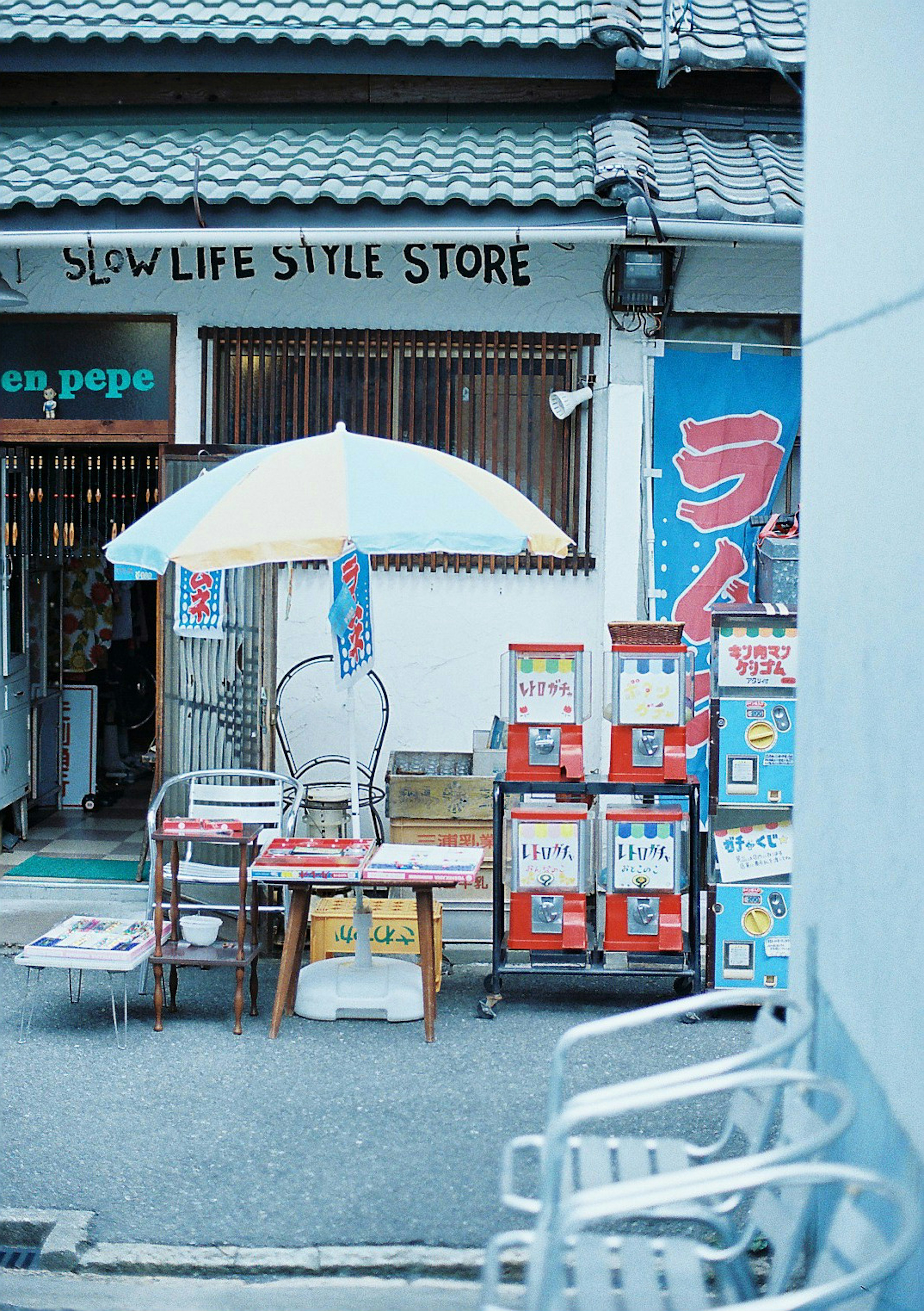 Exterior of a store featuring an umbrella and chairs with colorful signage