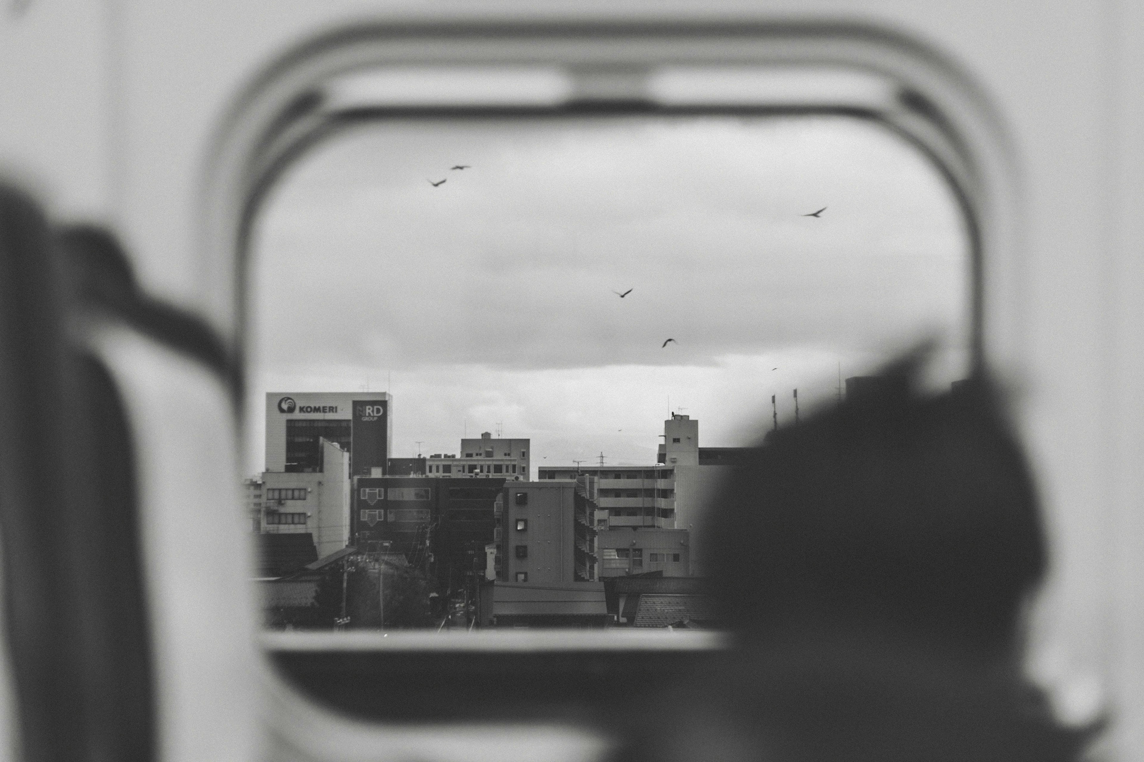 Stadtansicht durch ein Zugfenster mit bewölktem Himmel