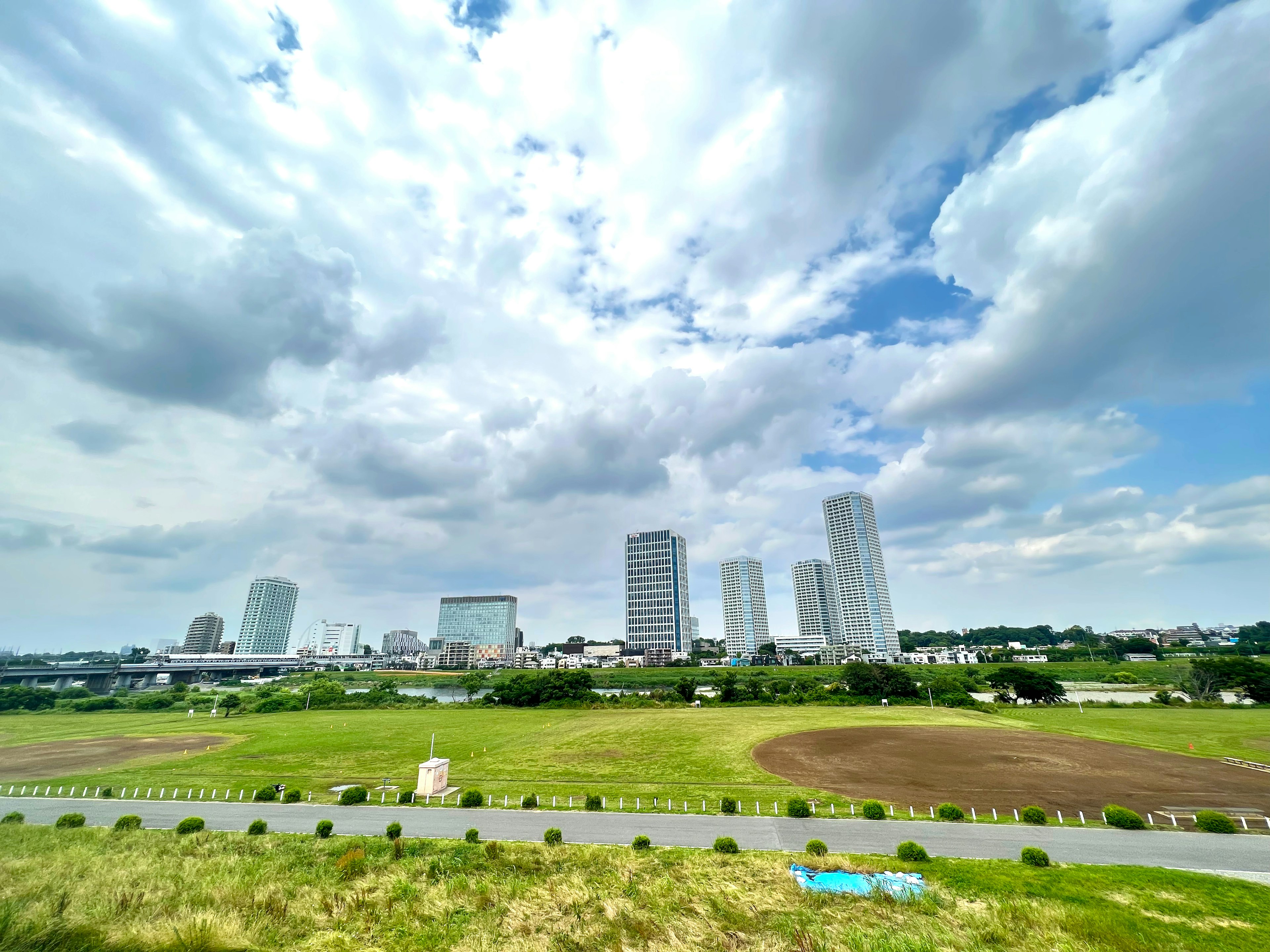 City skyline under a blue sky with lush green fields