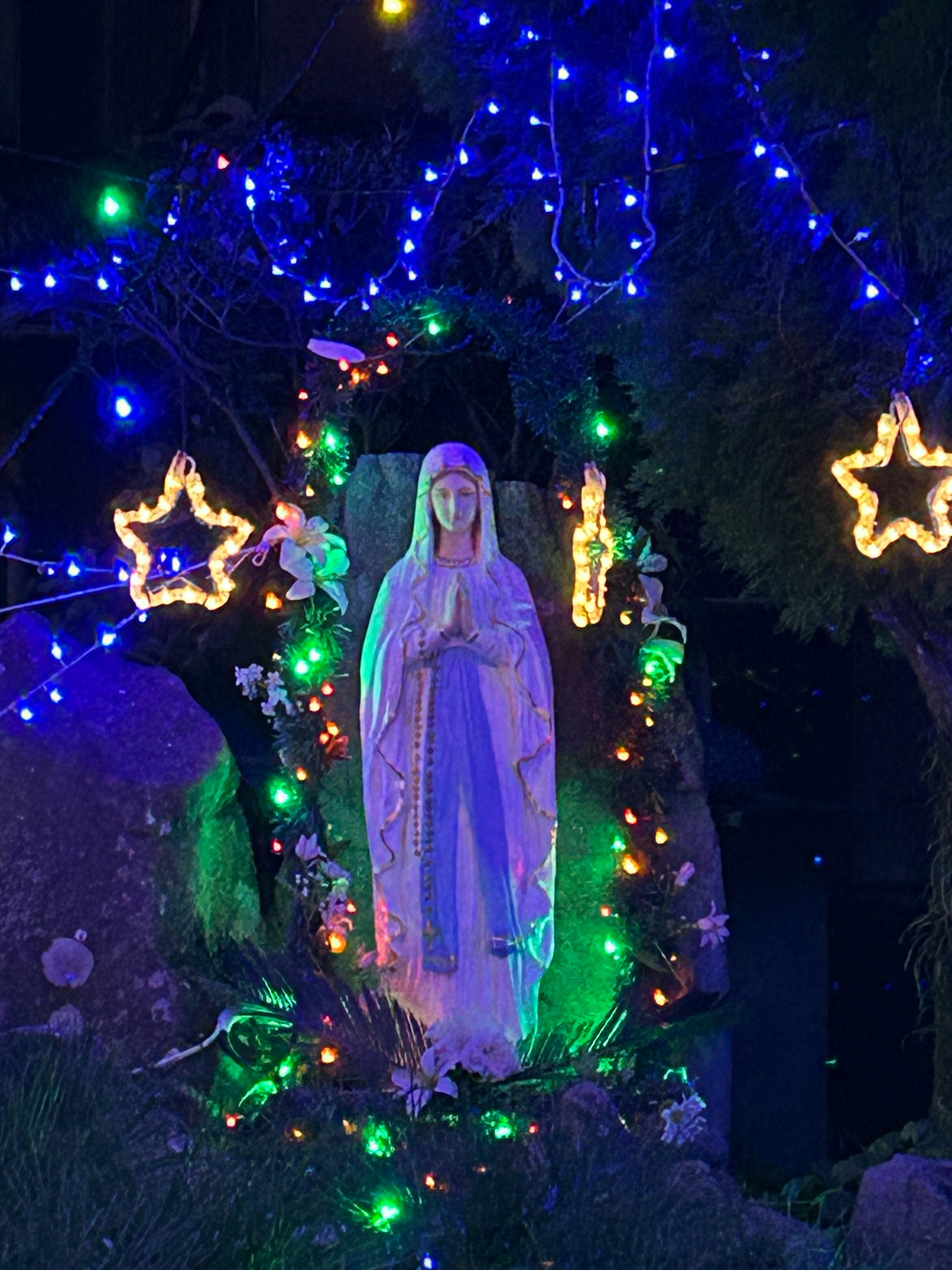 Statue of Virgin Mary surrounded by blue lights and star decorations