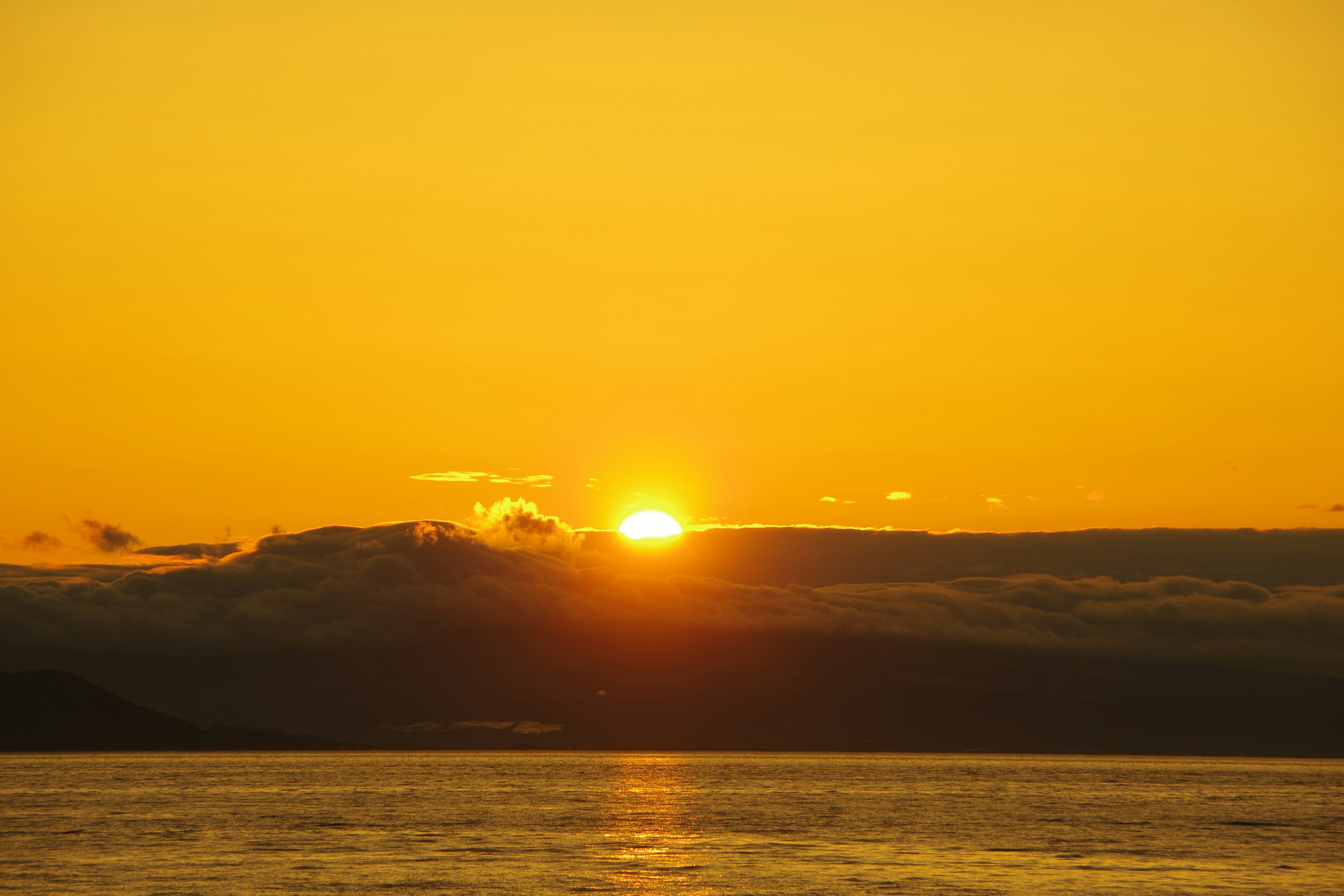 Una hermosa puesta de sol sobre el mar con un cielo naranja y nubes