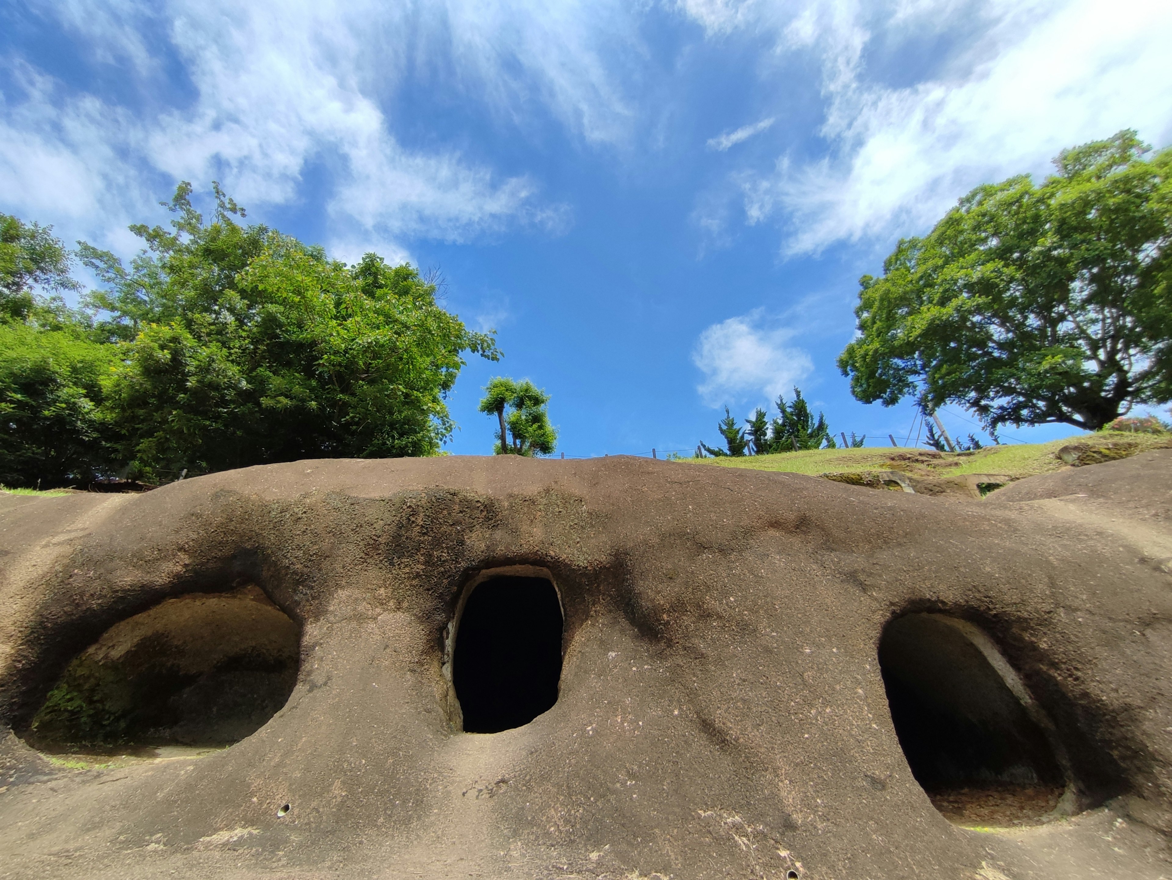 蓝天下的岩石洞穴与绿色植物的风景