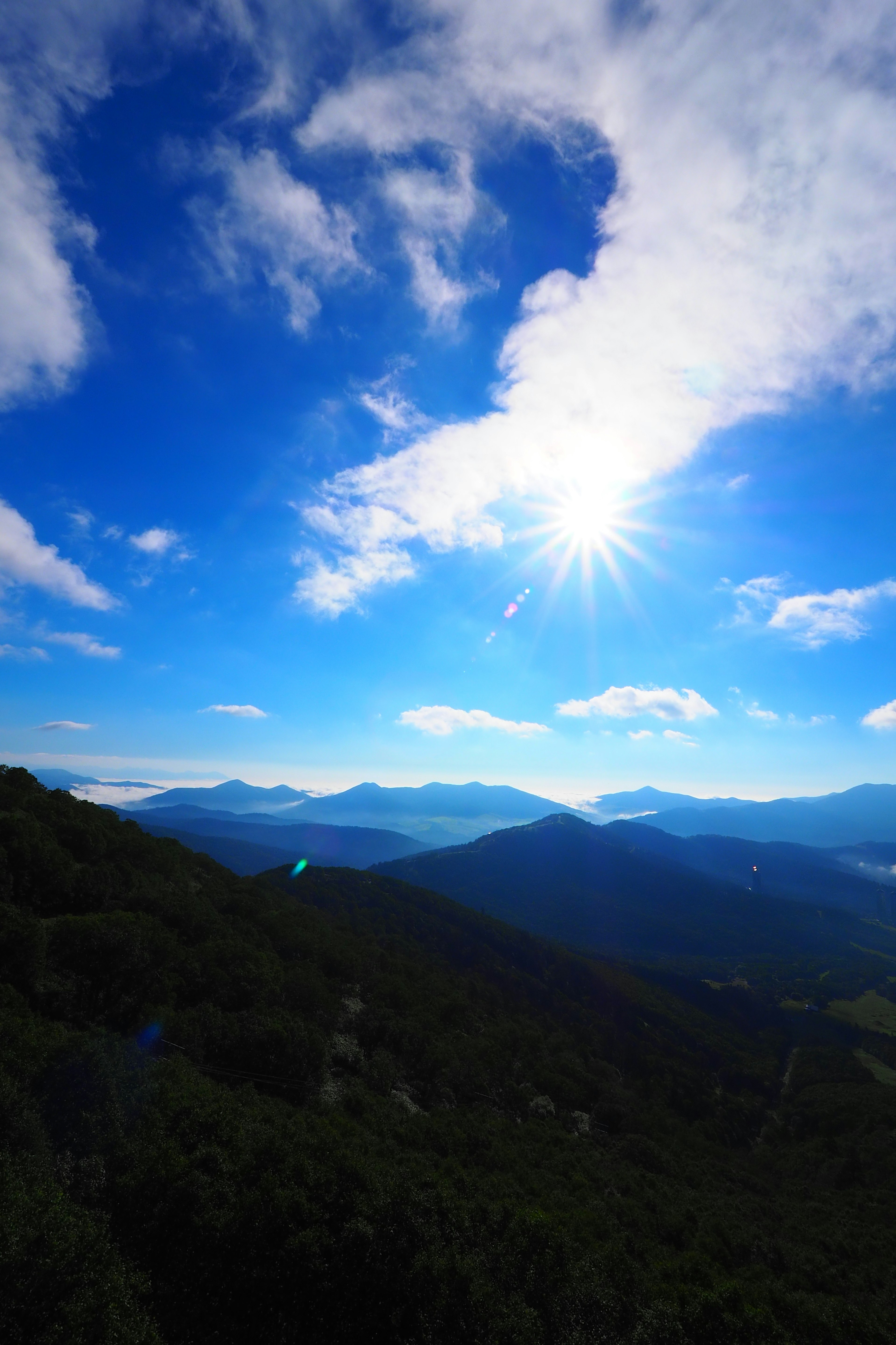 Paisaje montañoso con sol brillante y cielo azul