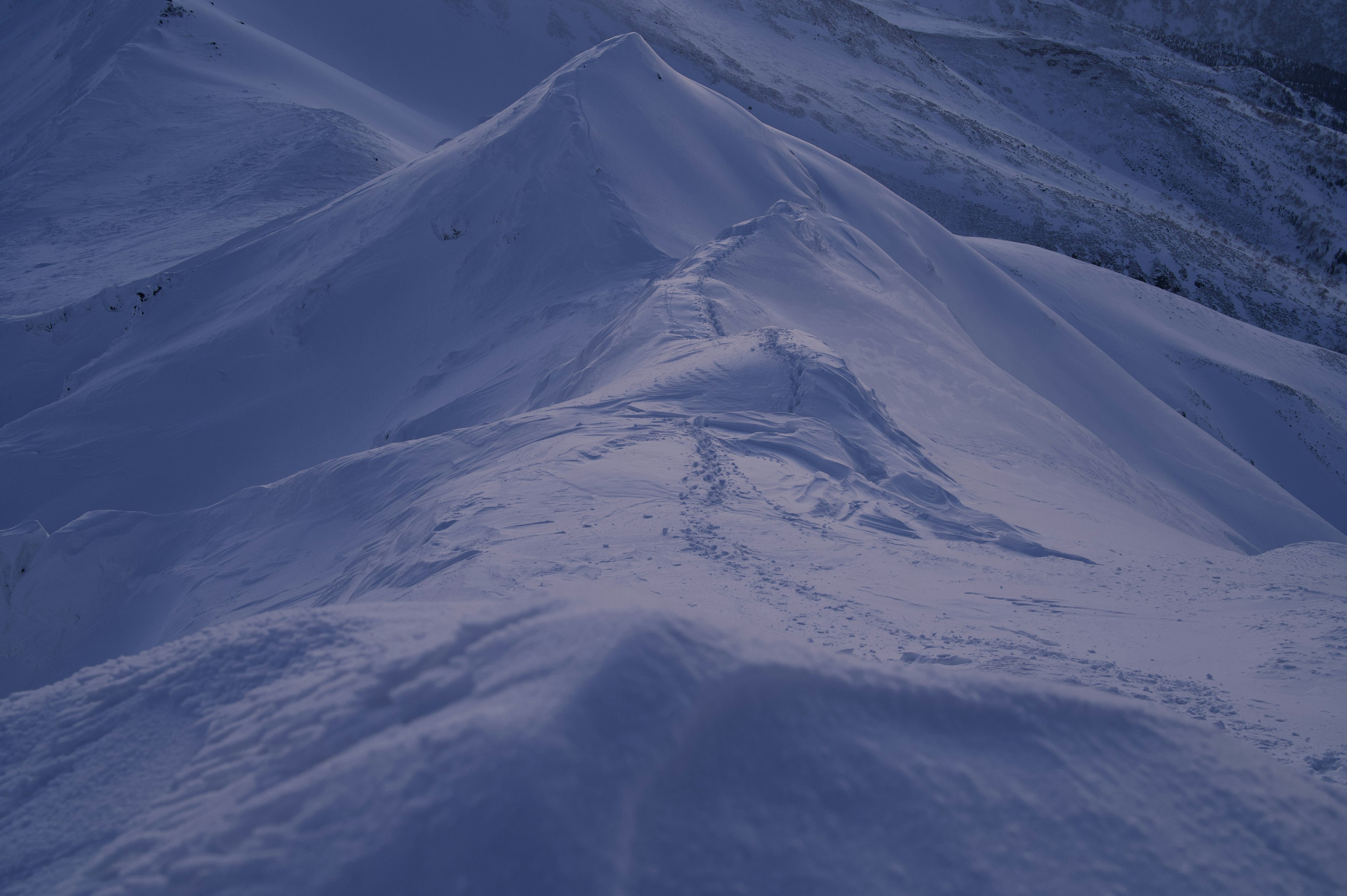 Paisaje montañoso cubierto de nieve con picos suaves