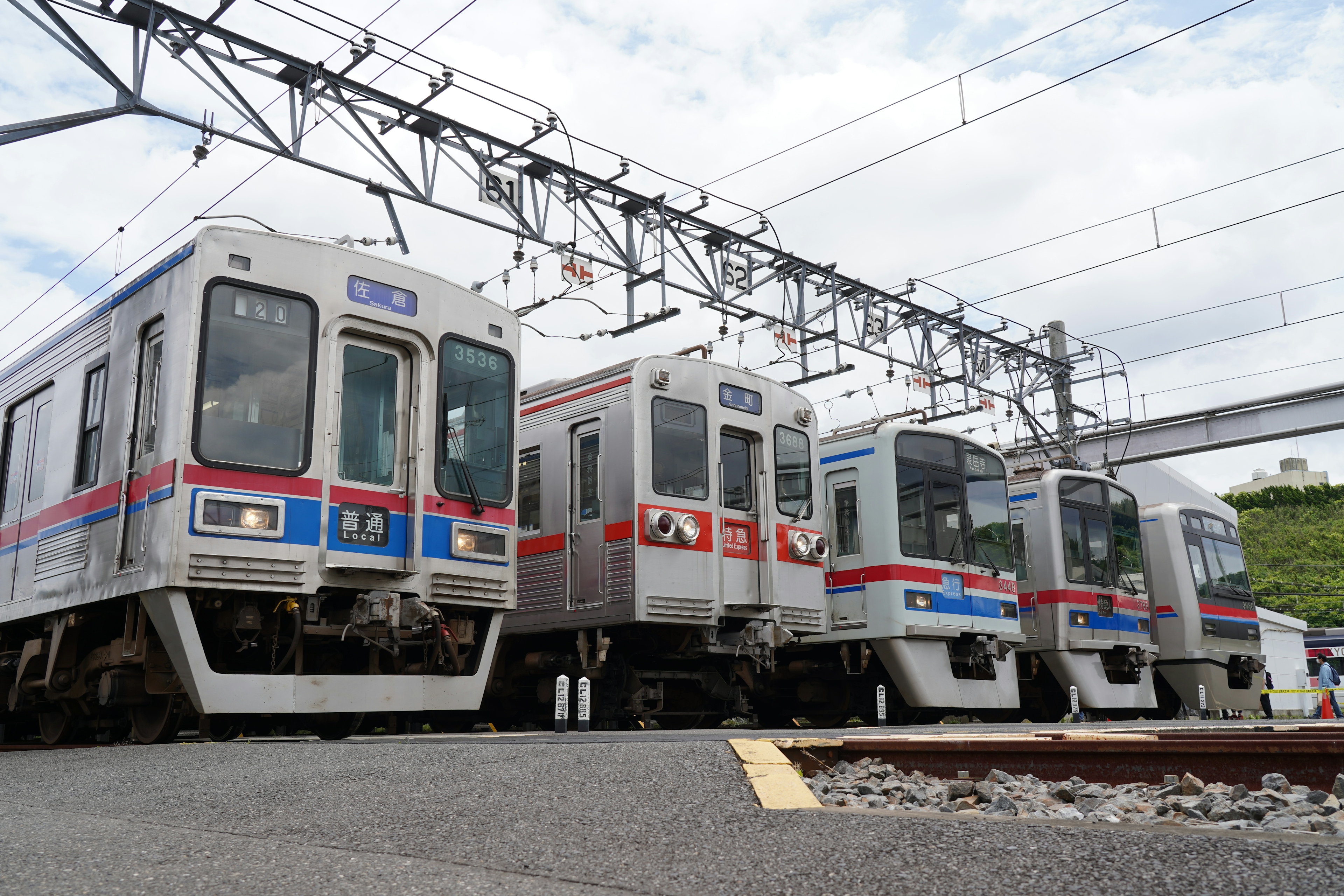 Several train cars lined up on railway tracks with overhead wires