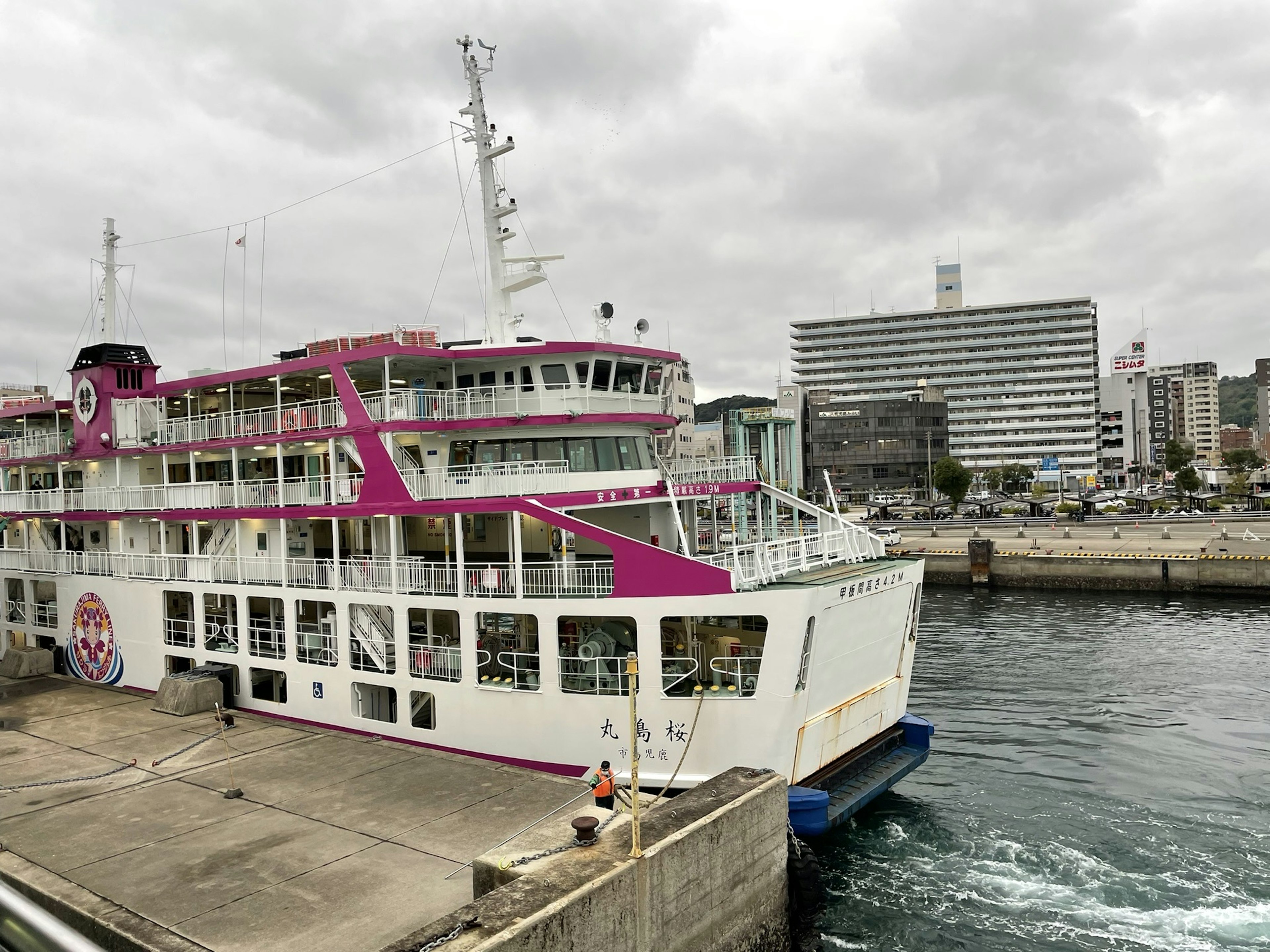 A large passenger ship with pink decorations docked at the harbor