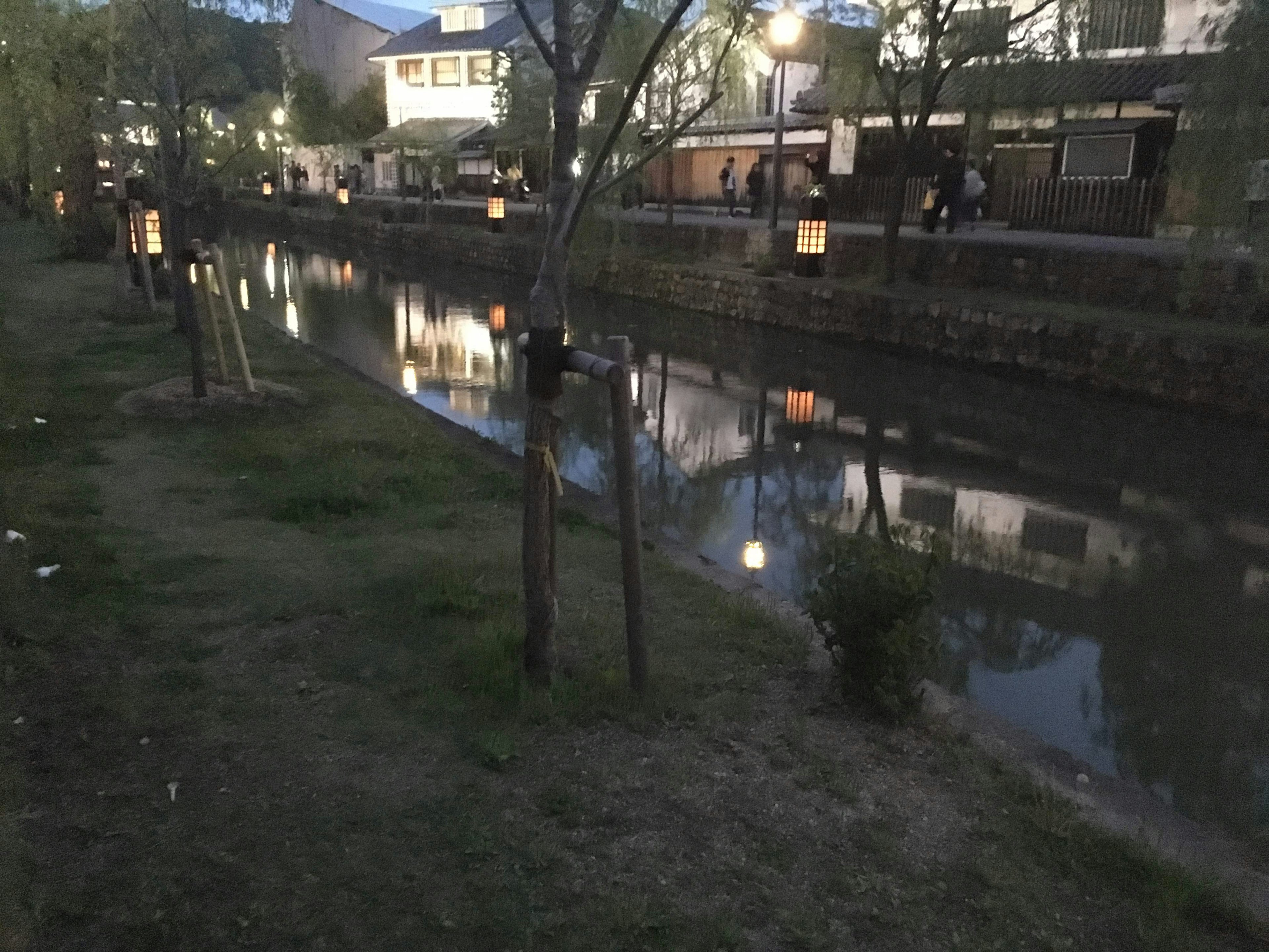 静かな水路に沿った灯篭と木々のある風景