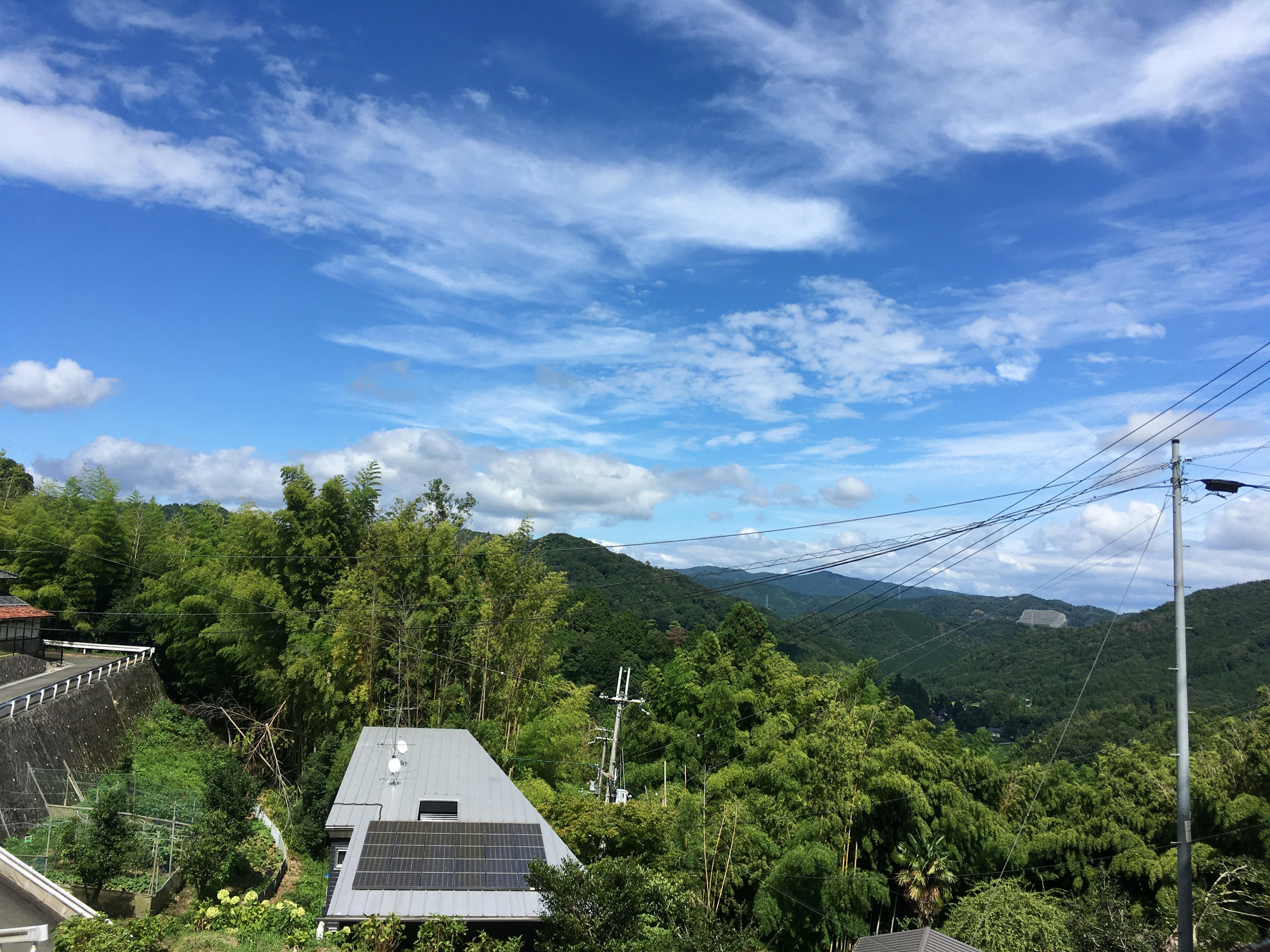 Pemandangan indah pegunungan hijau di bawah langit biru dengan atap panel surya