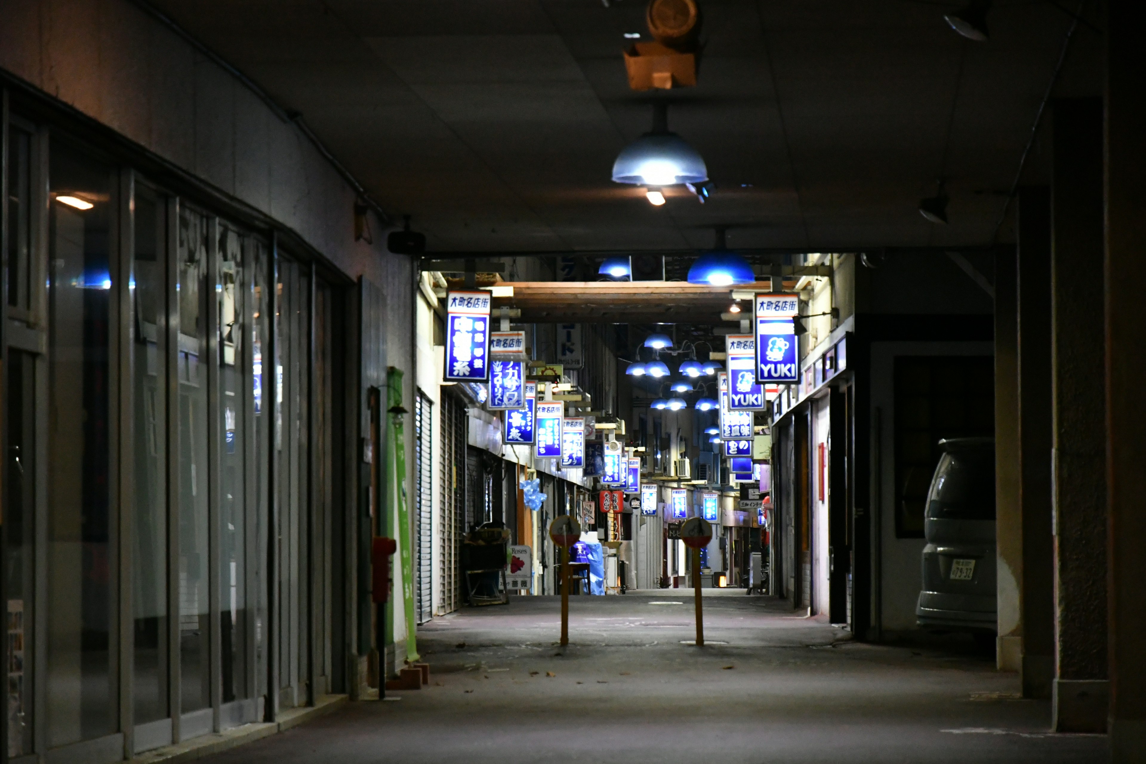 Pasillo débilmente iluminado con luces azules y tiendas