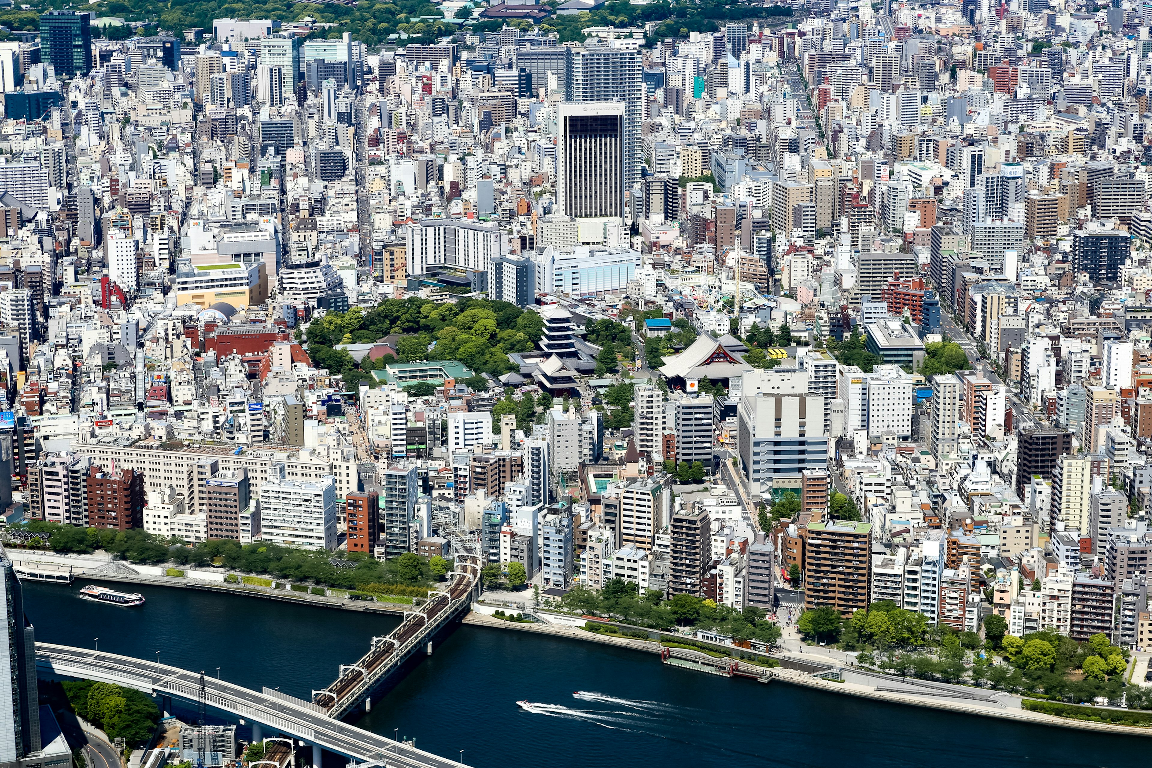 Aerial view of Tokyo featuring skyscrapers and a river green spaces and numerous buildings