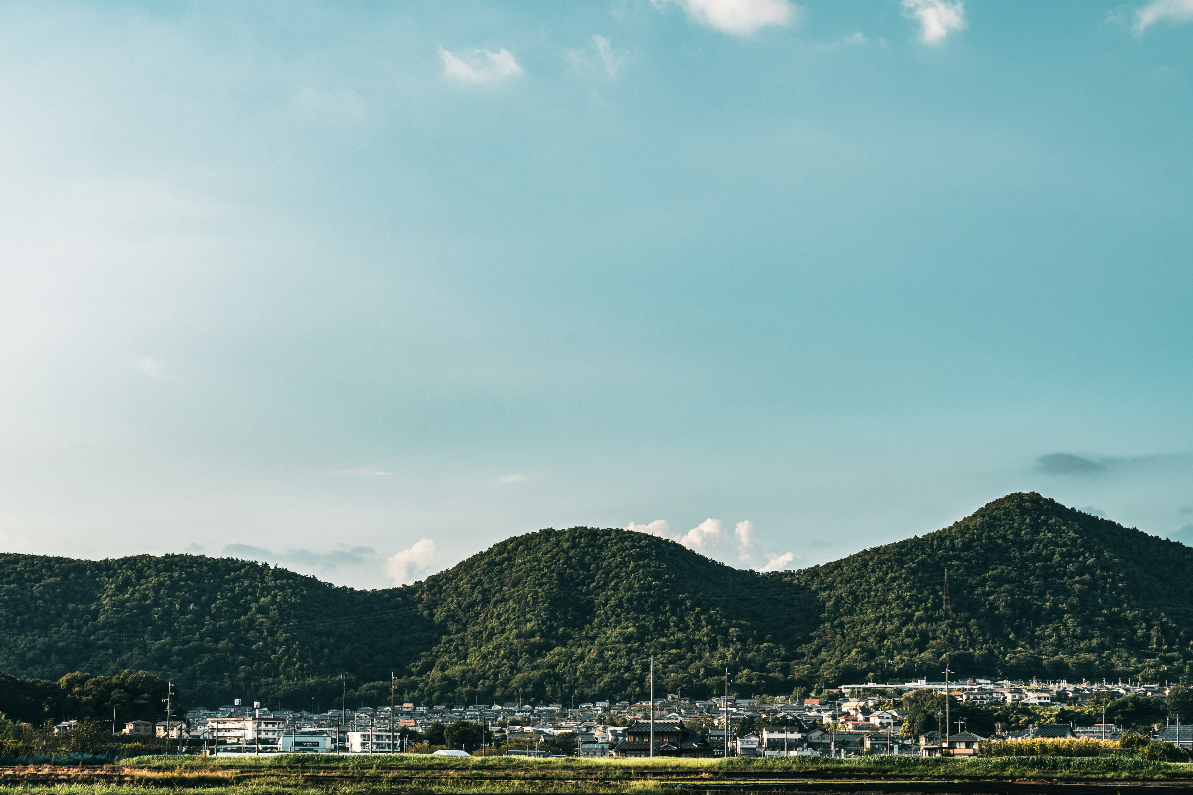 青空の下に広がる緑の山々とその麓にある小さな街並み