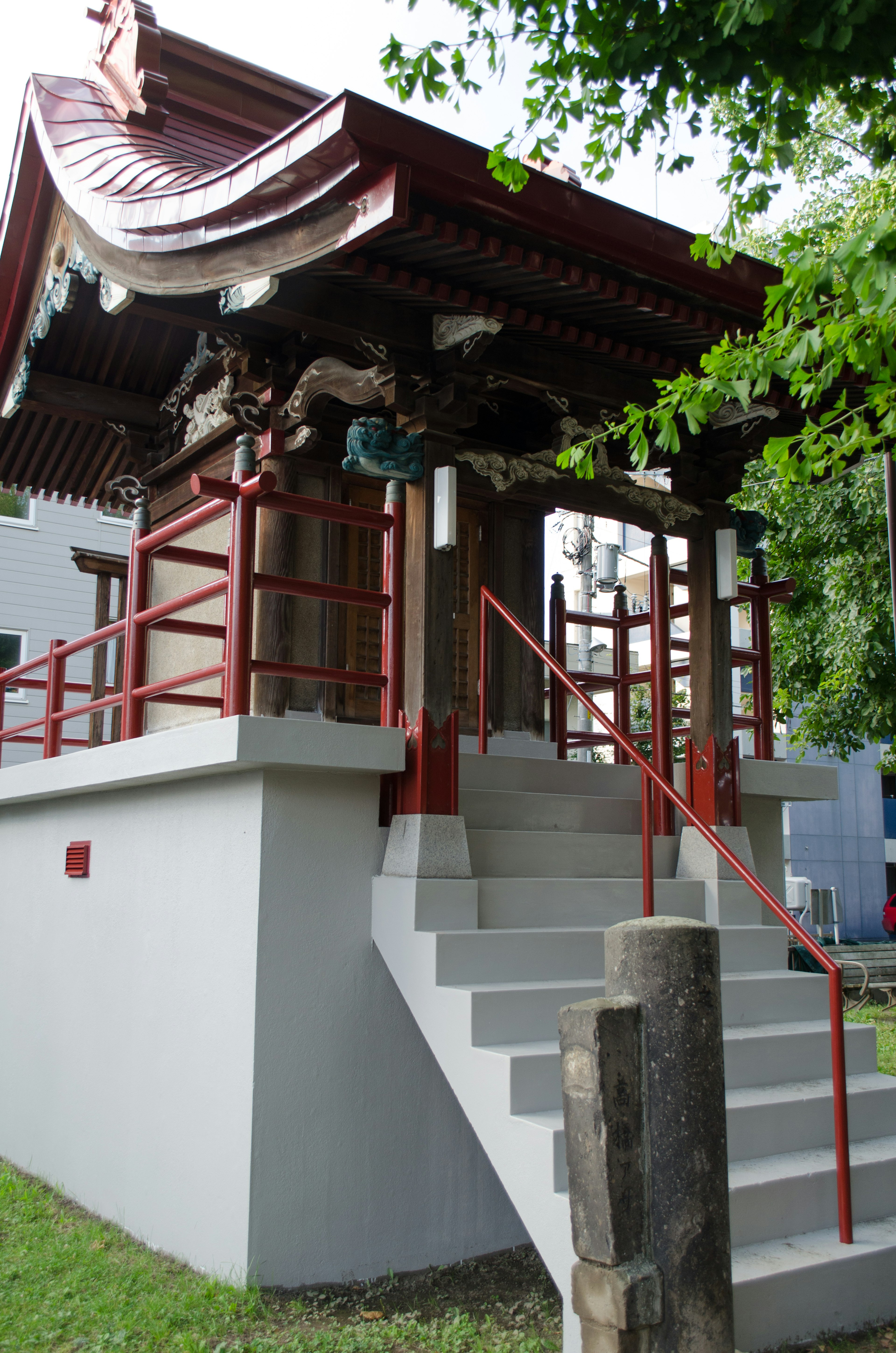 赤い屋根の神社の階段と木製の柱が特徴