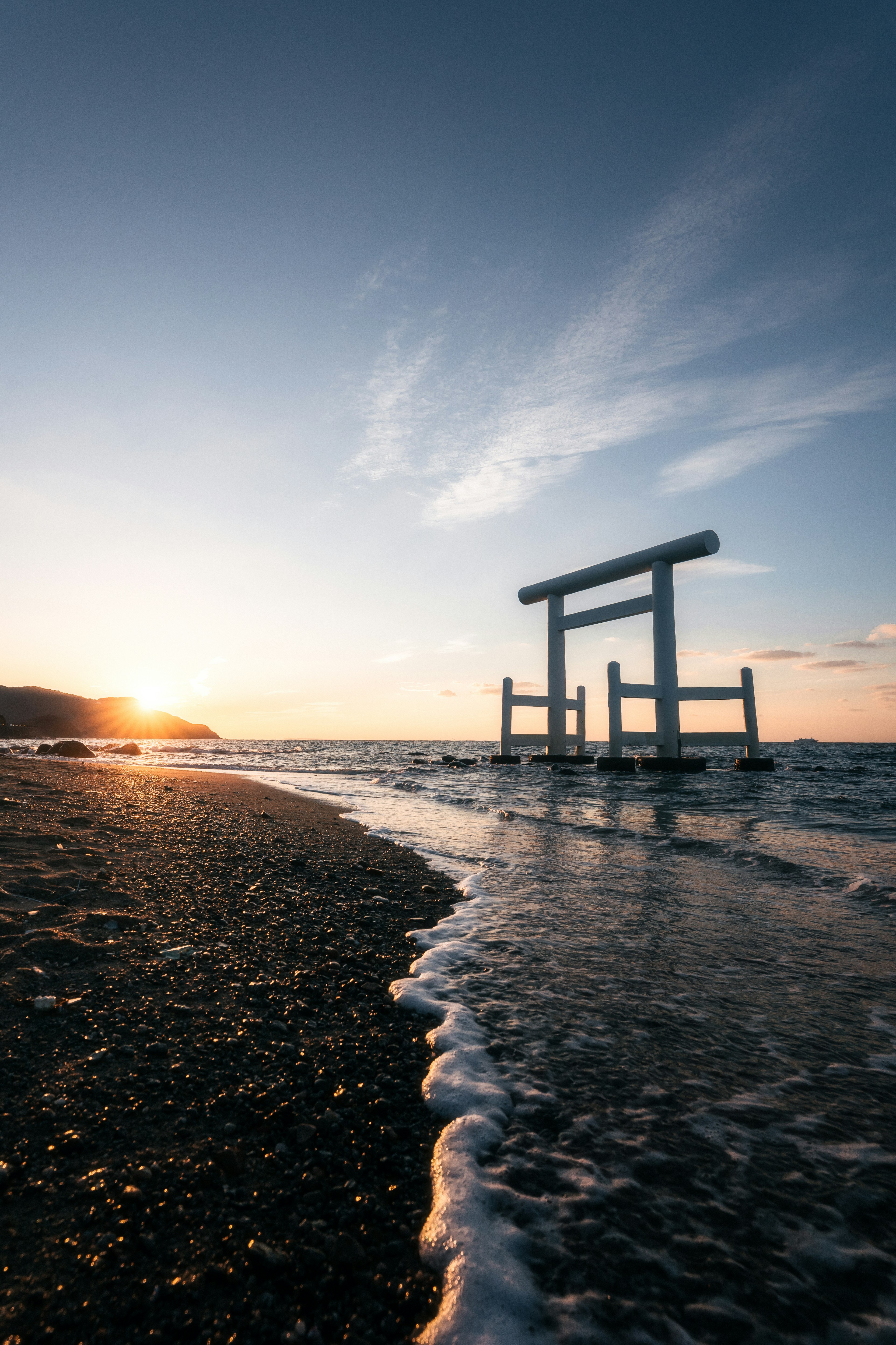 Un torii sulla spiaggia con un bellissimo tramonto