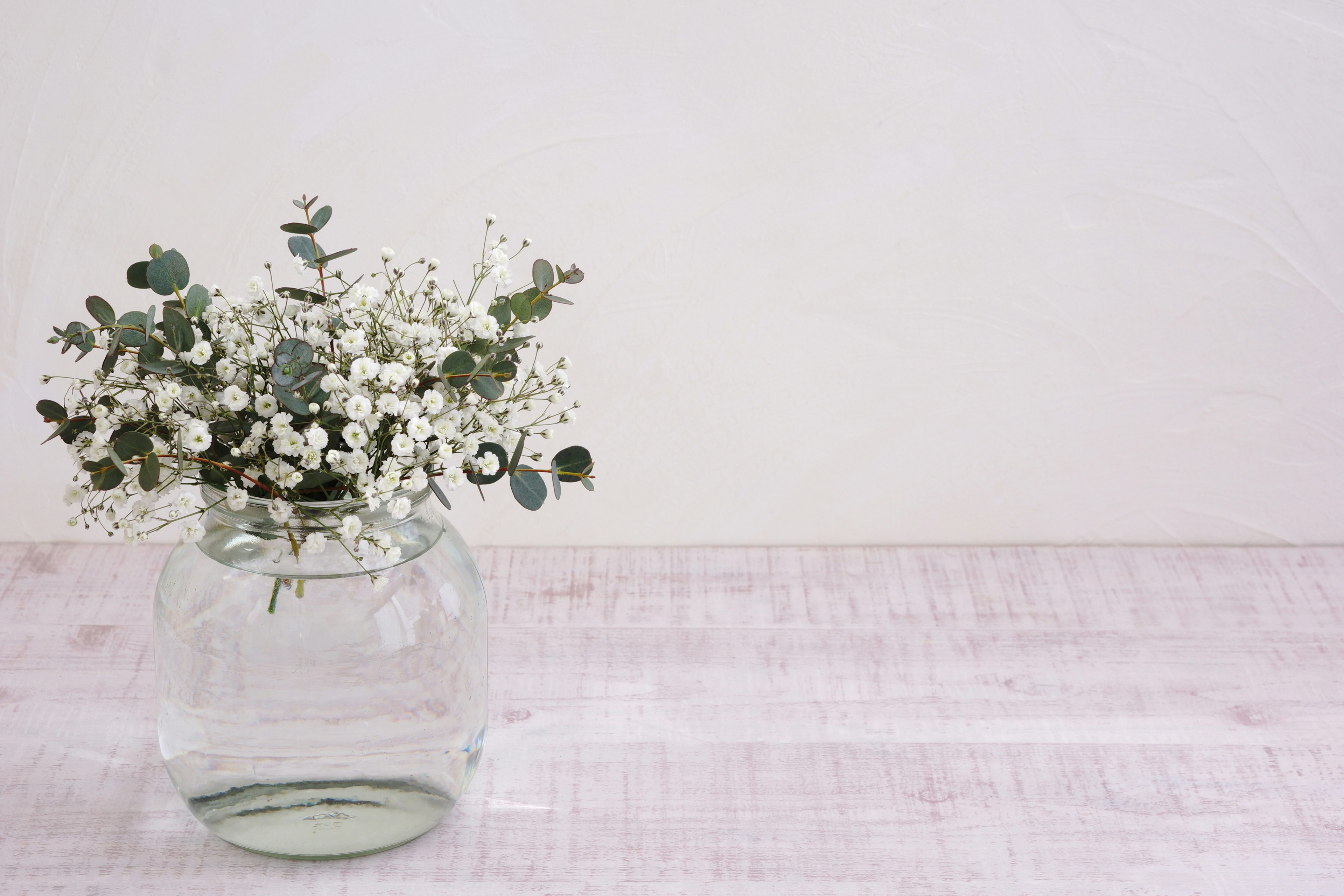 Simple arrangement of white flowers and eucalyptus leaves in a clear vase