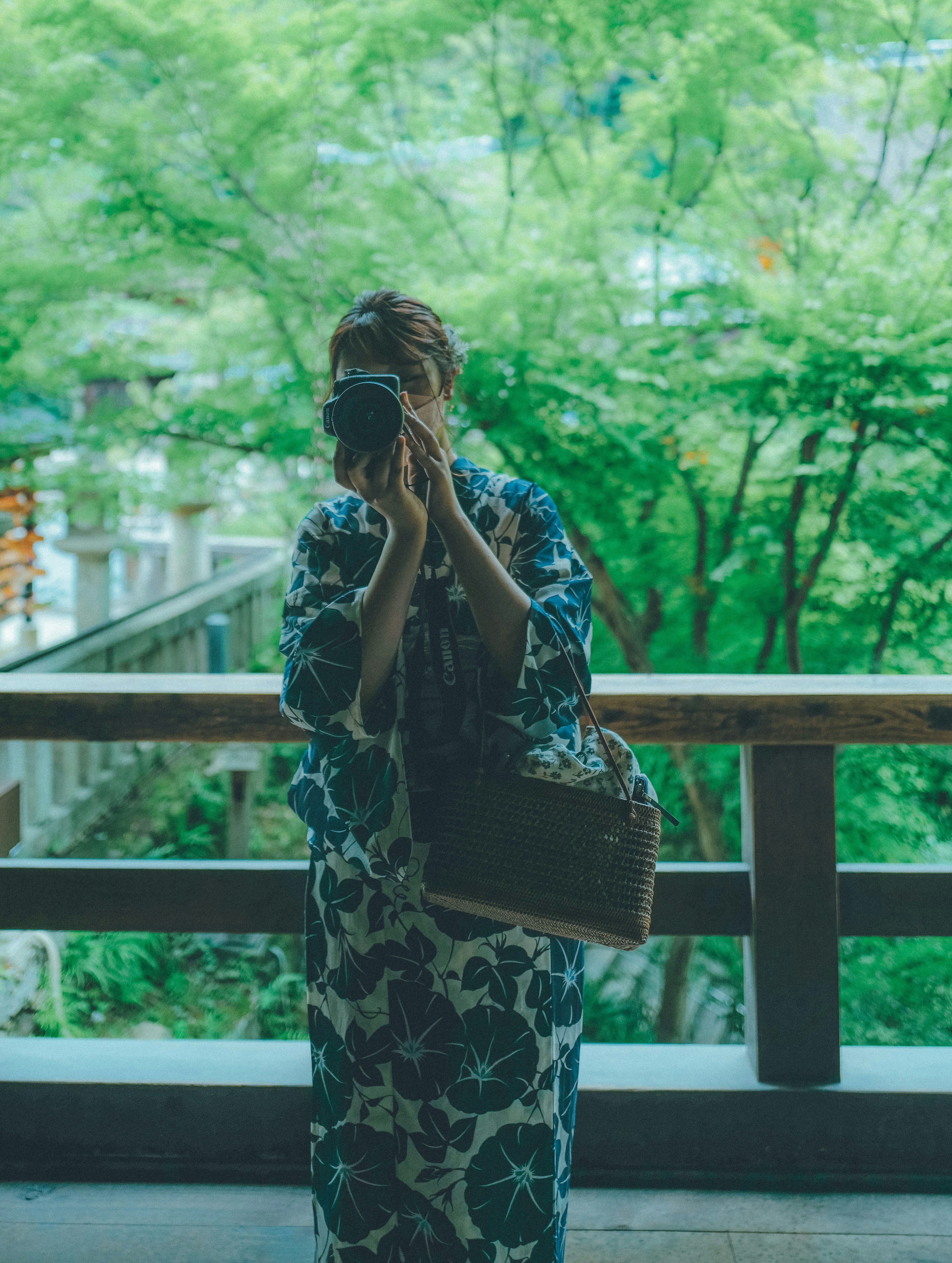 Mujer en kimono sosteniendo una cámara contra un fondo verde