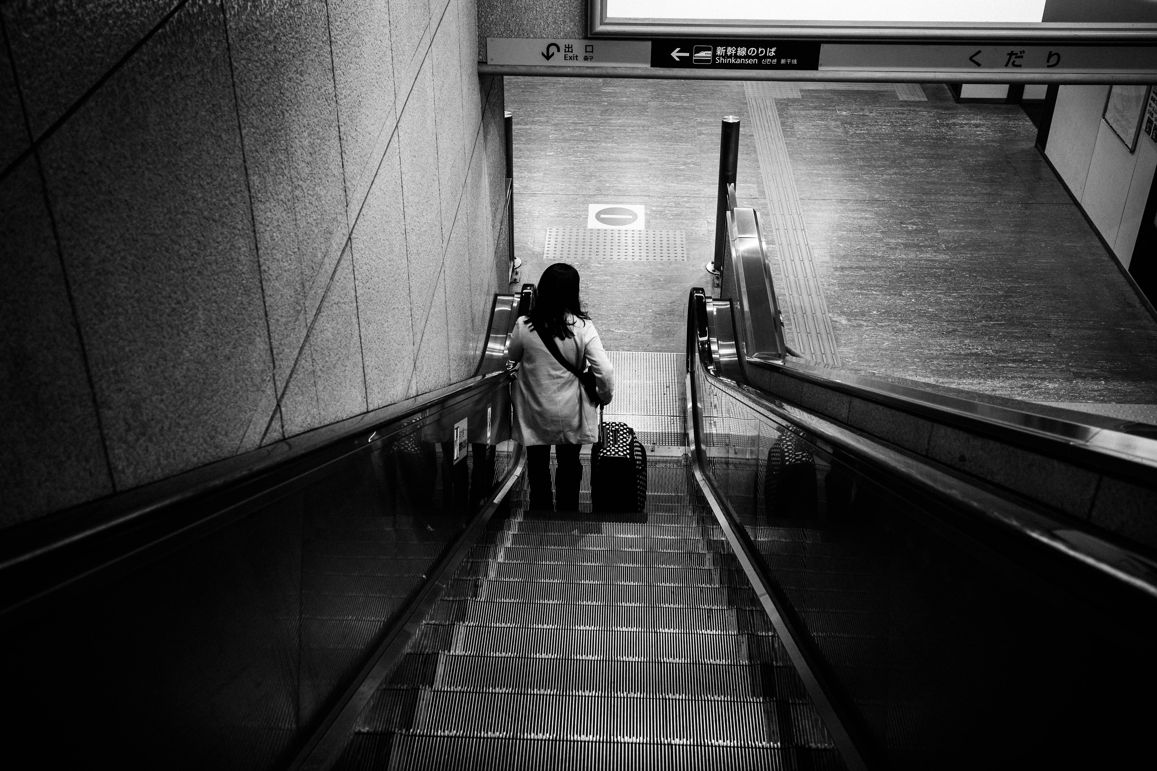 Femme descendant des escaliers avec une valise photo en noir et blanc