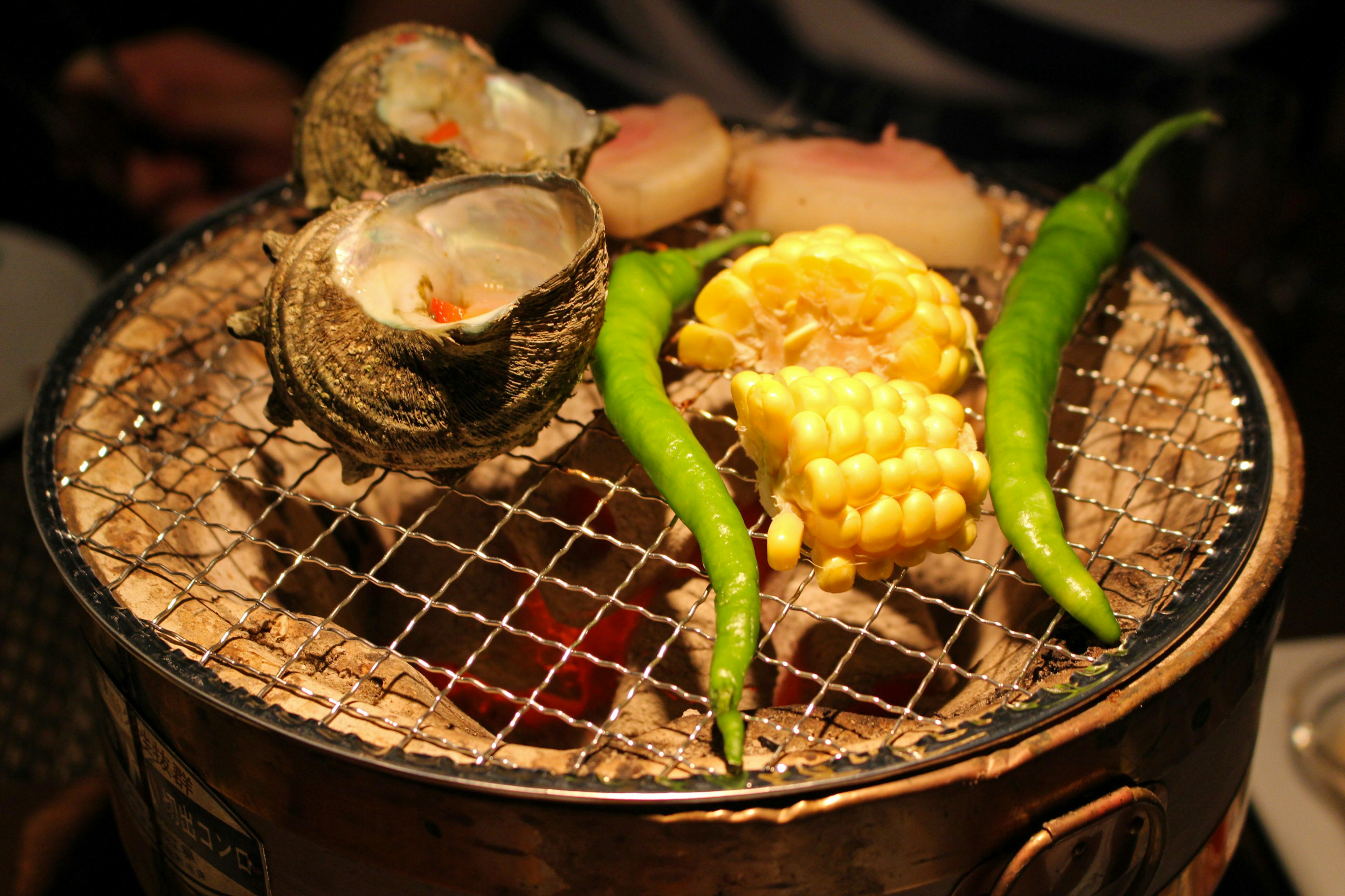 Grill with oysters, corn, and green chili peppers on top