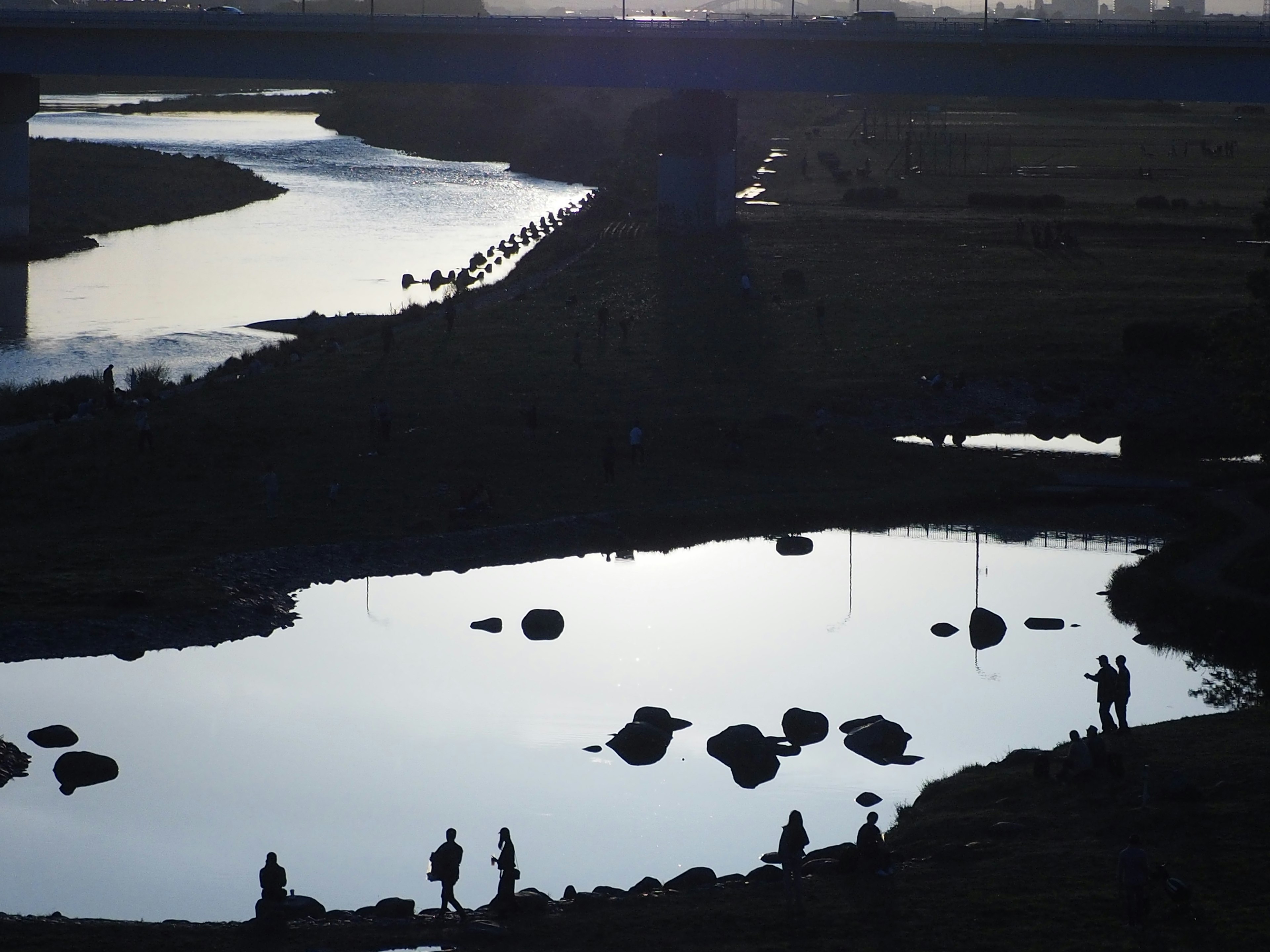 Pemandangan sungai tenang dengan siluet orang