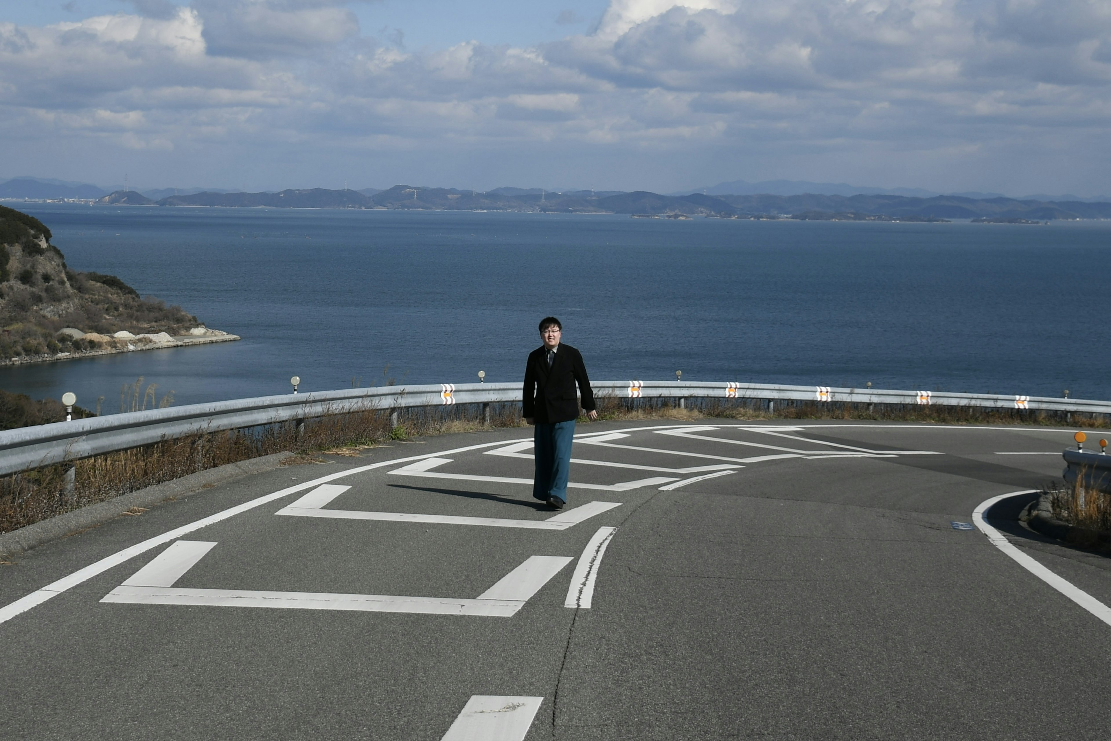 Una persona che cammina su una strada curva vicino al mare