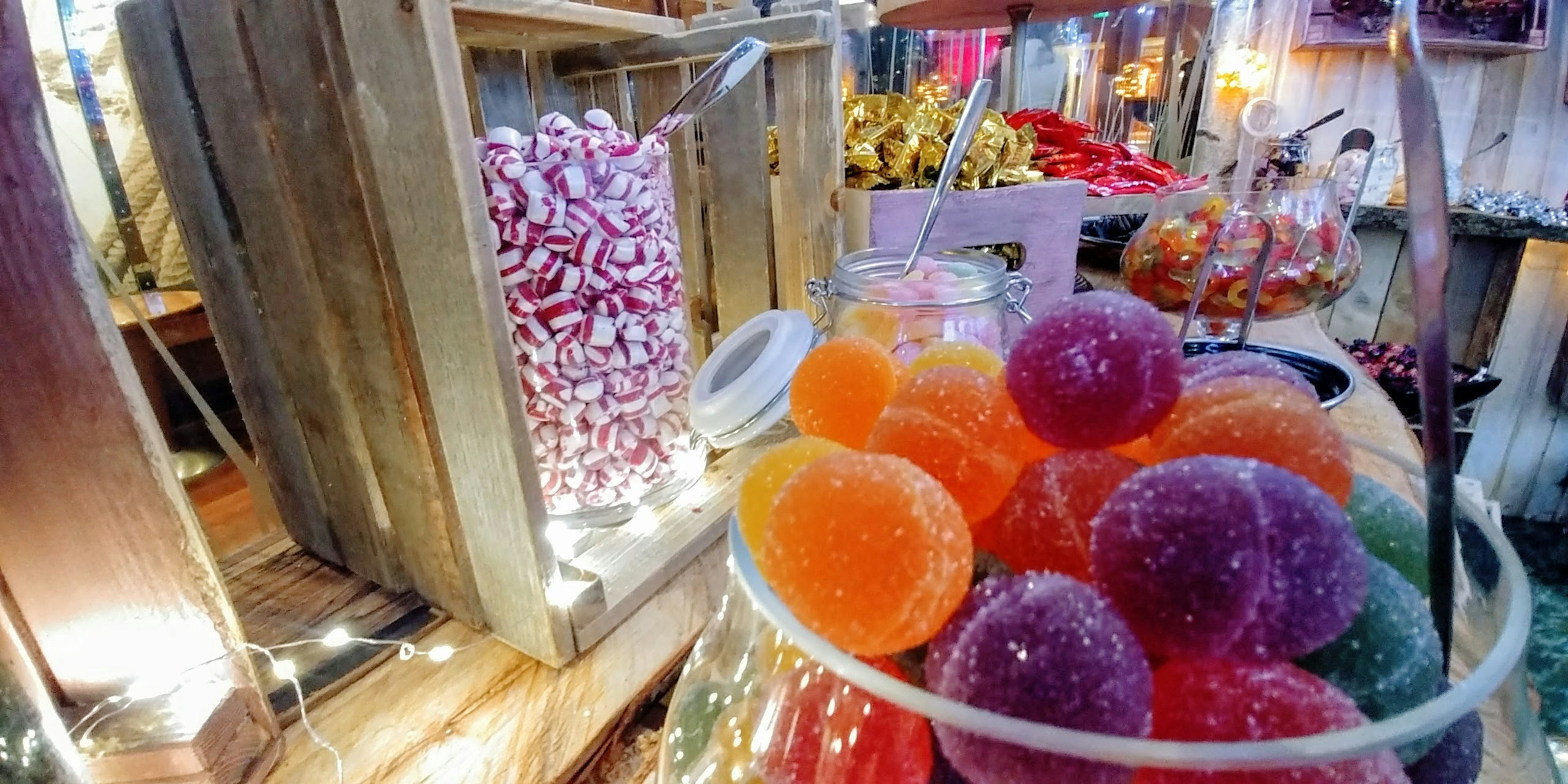 Dulces de gelatina coloridos en un tazón transparente con exhibidor de madera en una tienda de golosinas