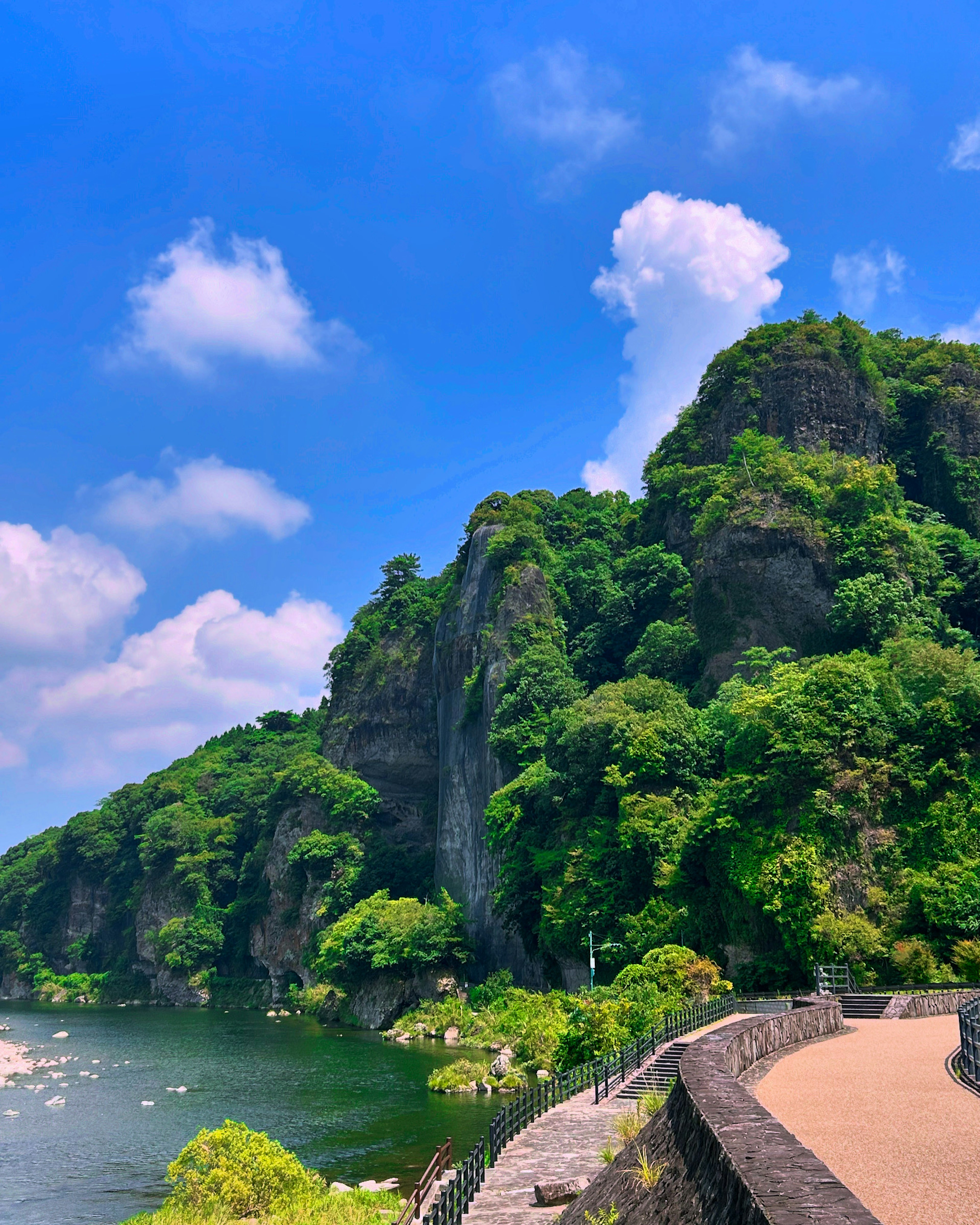 青空と緑豊かな山々が広がる風景に川が流れる