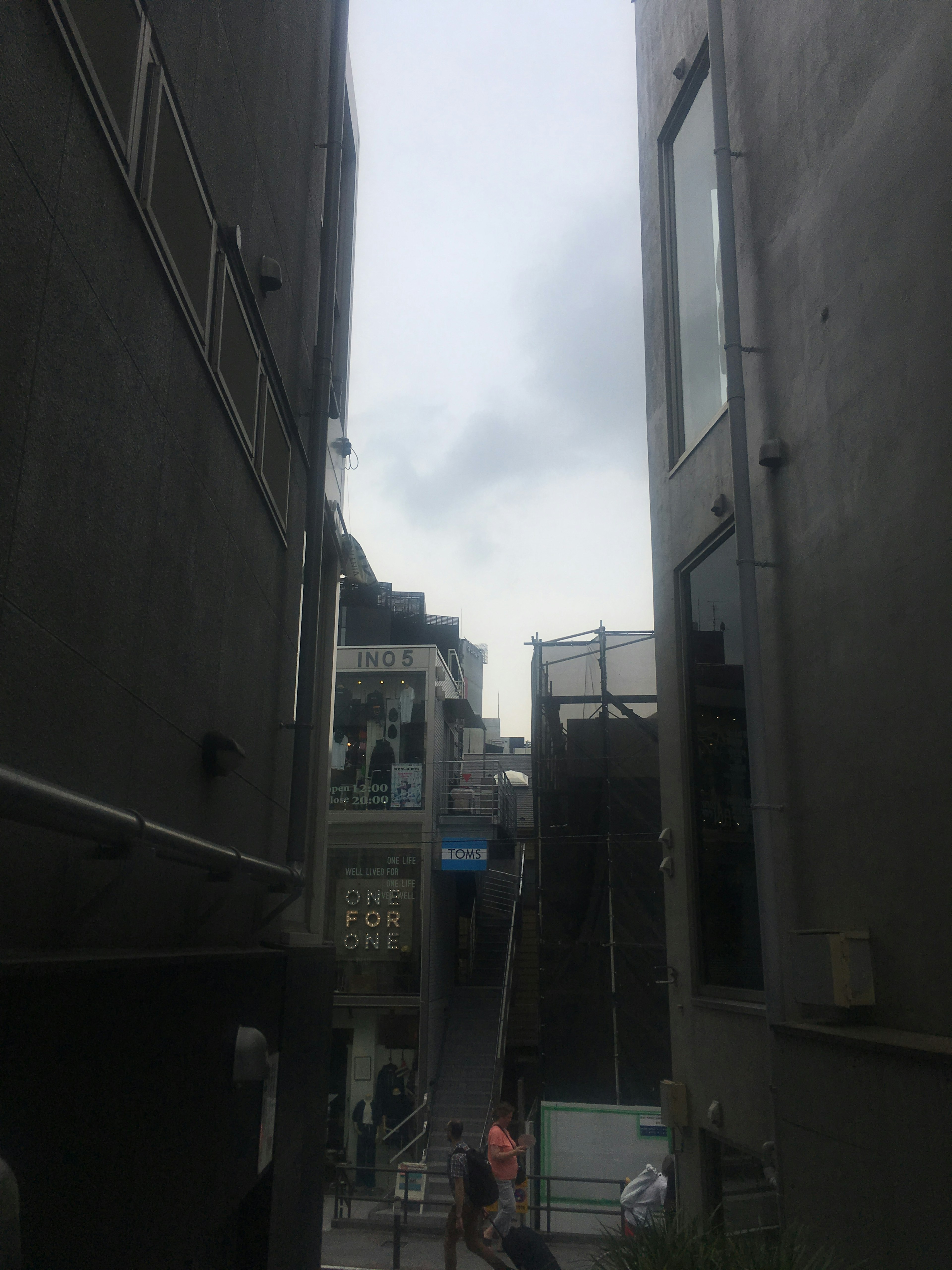 Narrow alley between buildings with cloudy sky