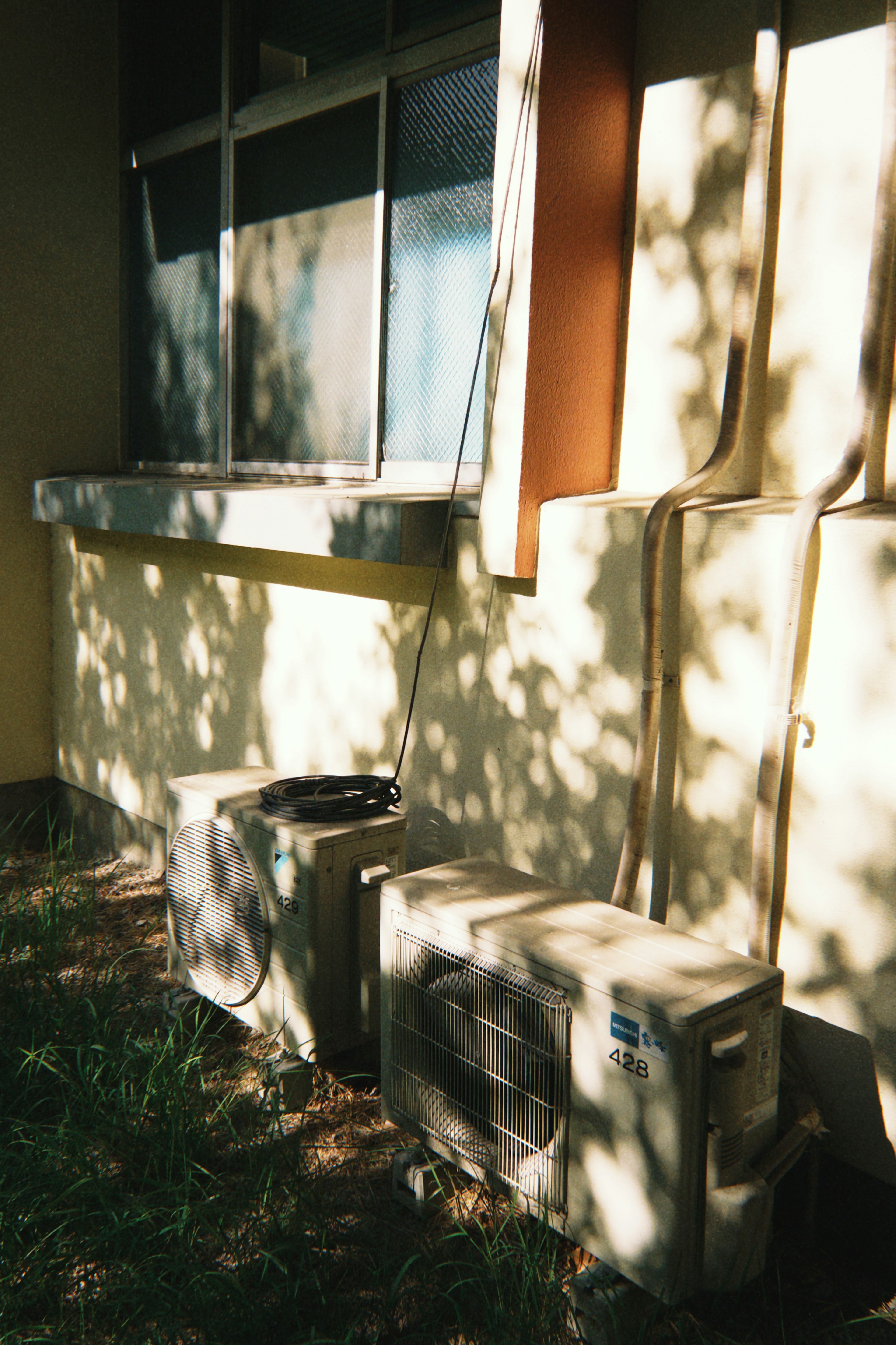 Air conditioning units placed near a building wall with shadows