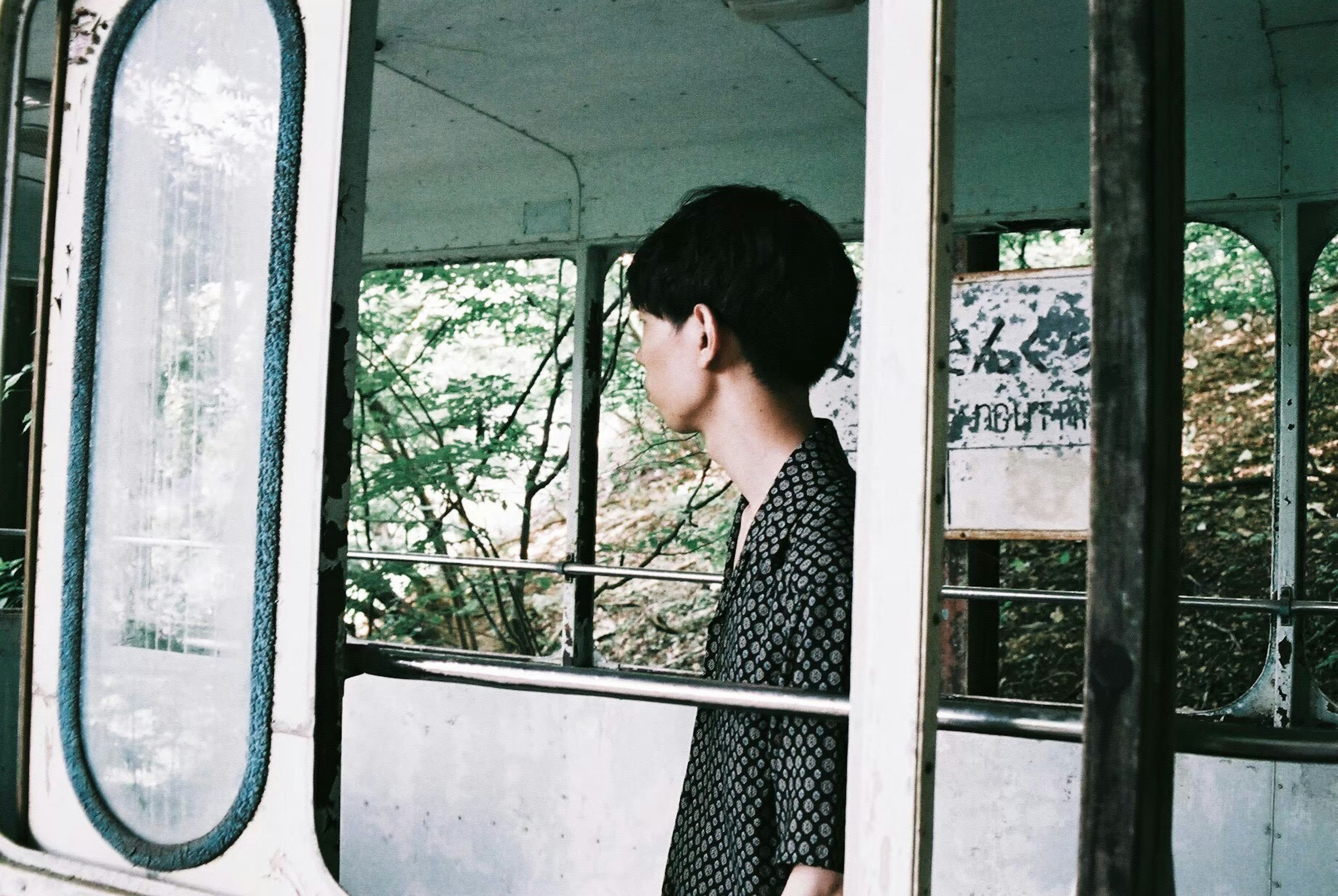 Side profile of a young man looking out the window with a green background