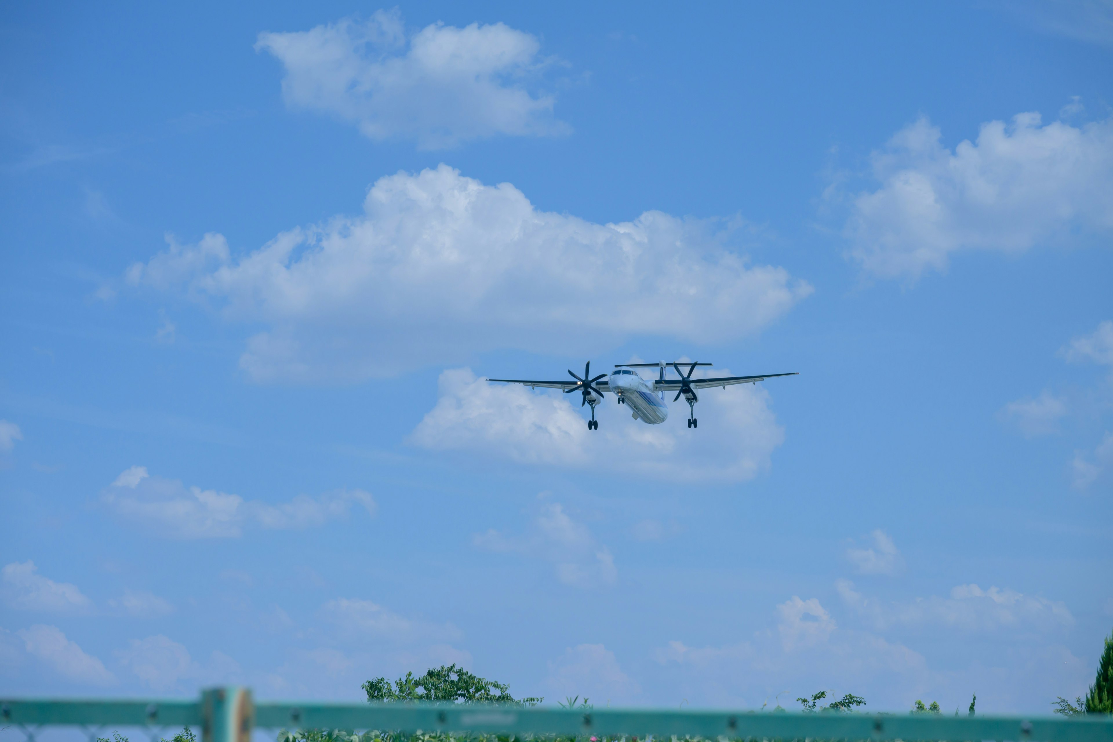 An airplane flying in a blue sky with clouds