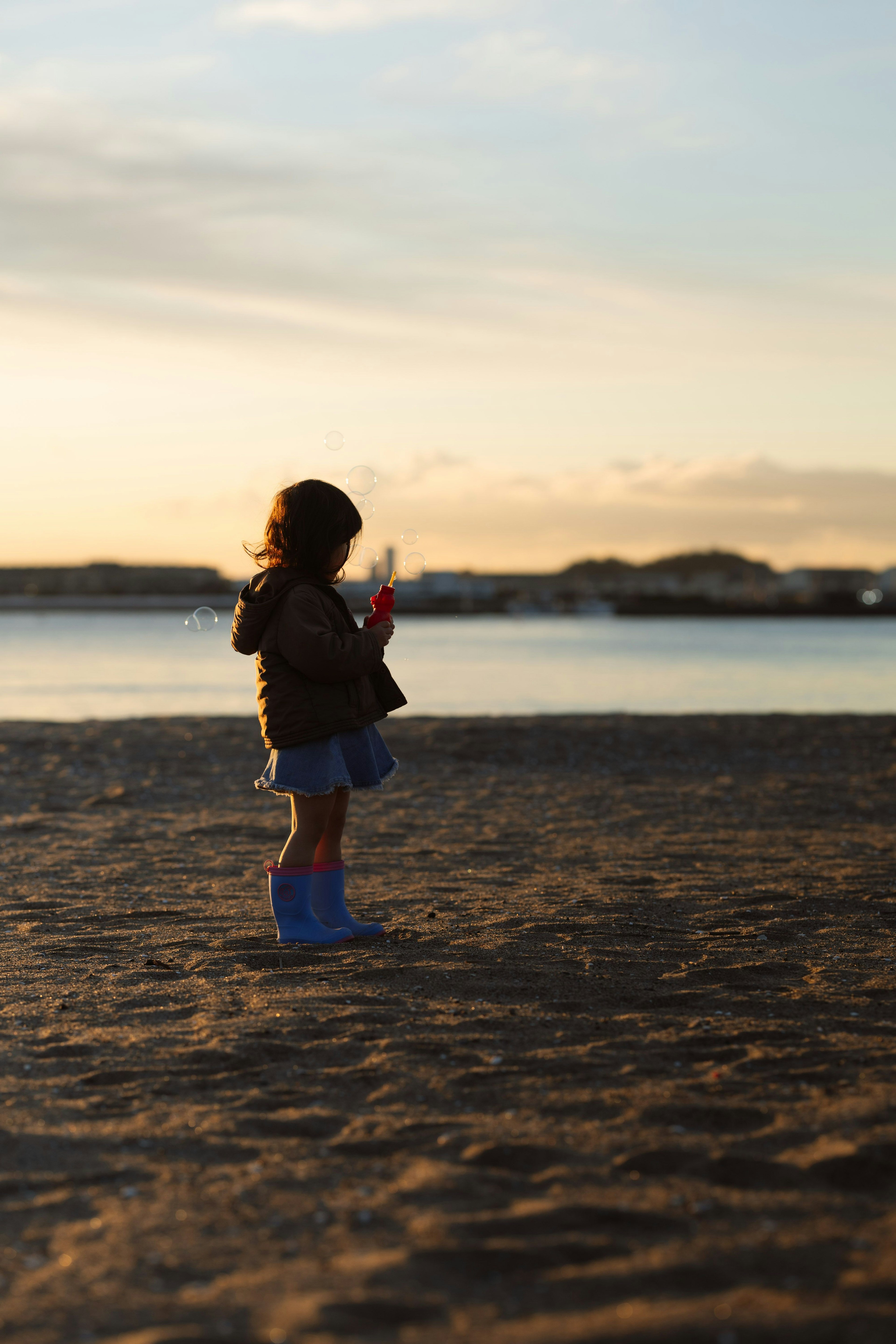 夕日を背景に砂浜に立つ子供のシルエット