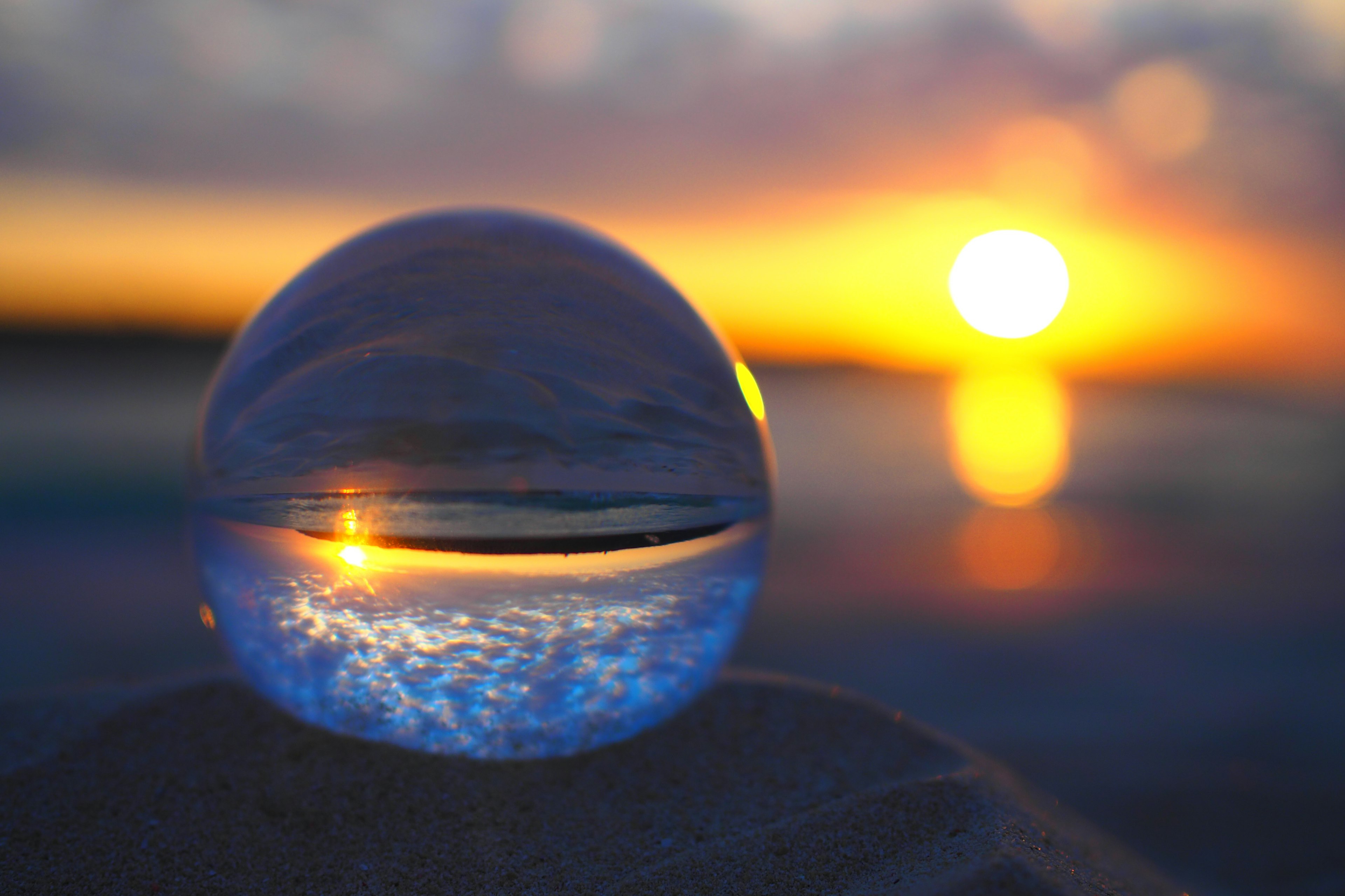 Una sfera di cristallo che riflette il tramonto su una spiaggia di sabbia