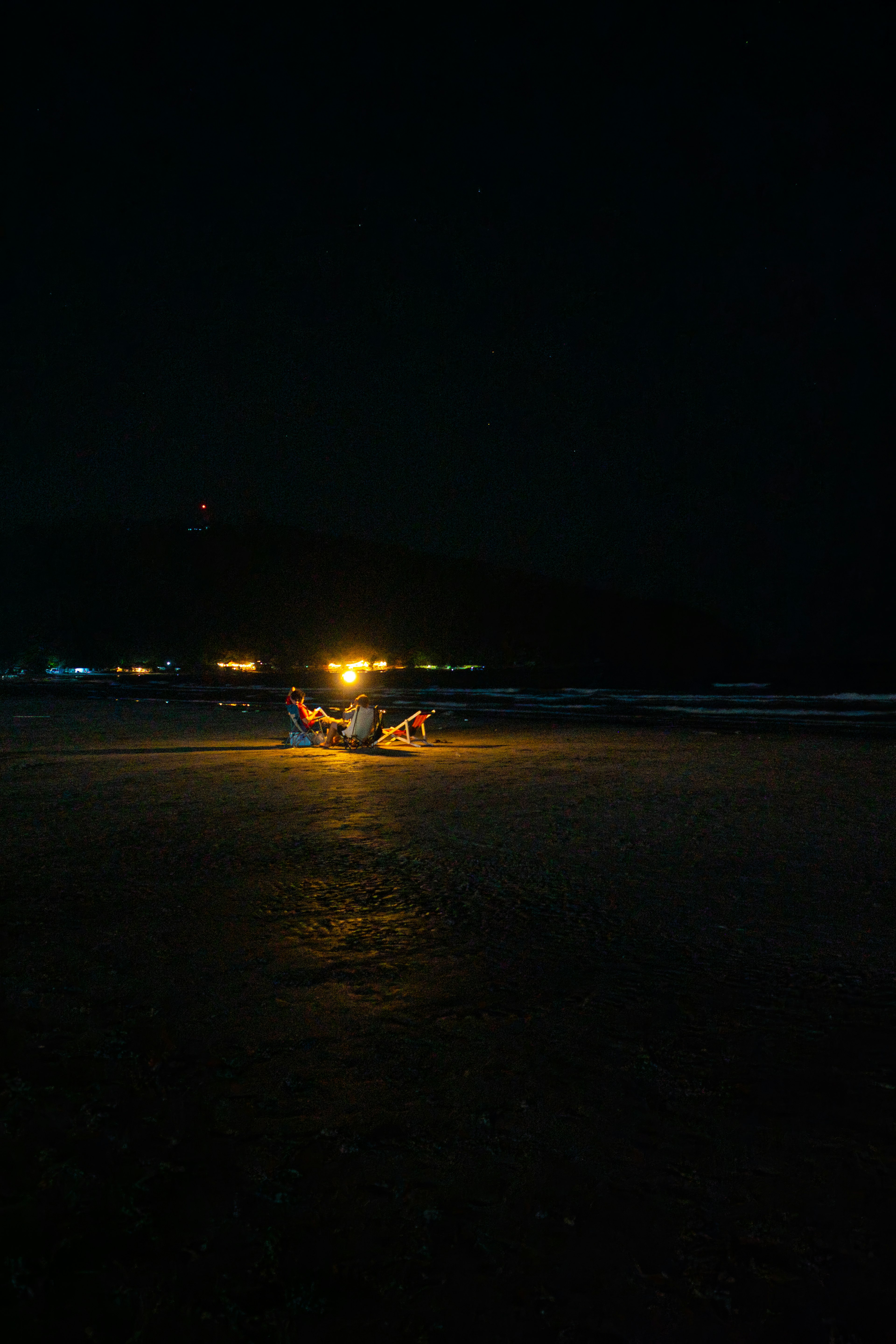 夜の浜辺で明るい光を持つ小舟と人々