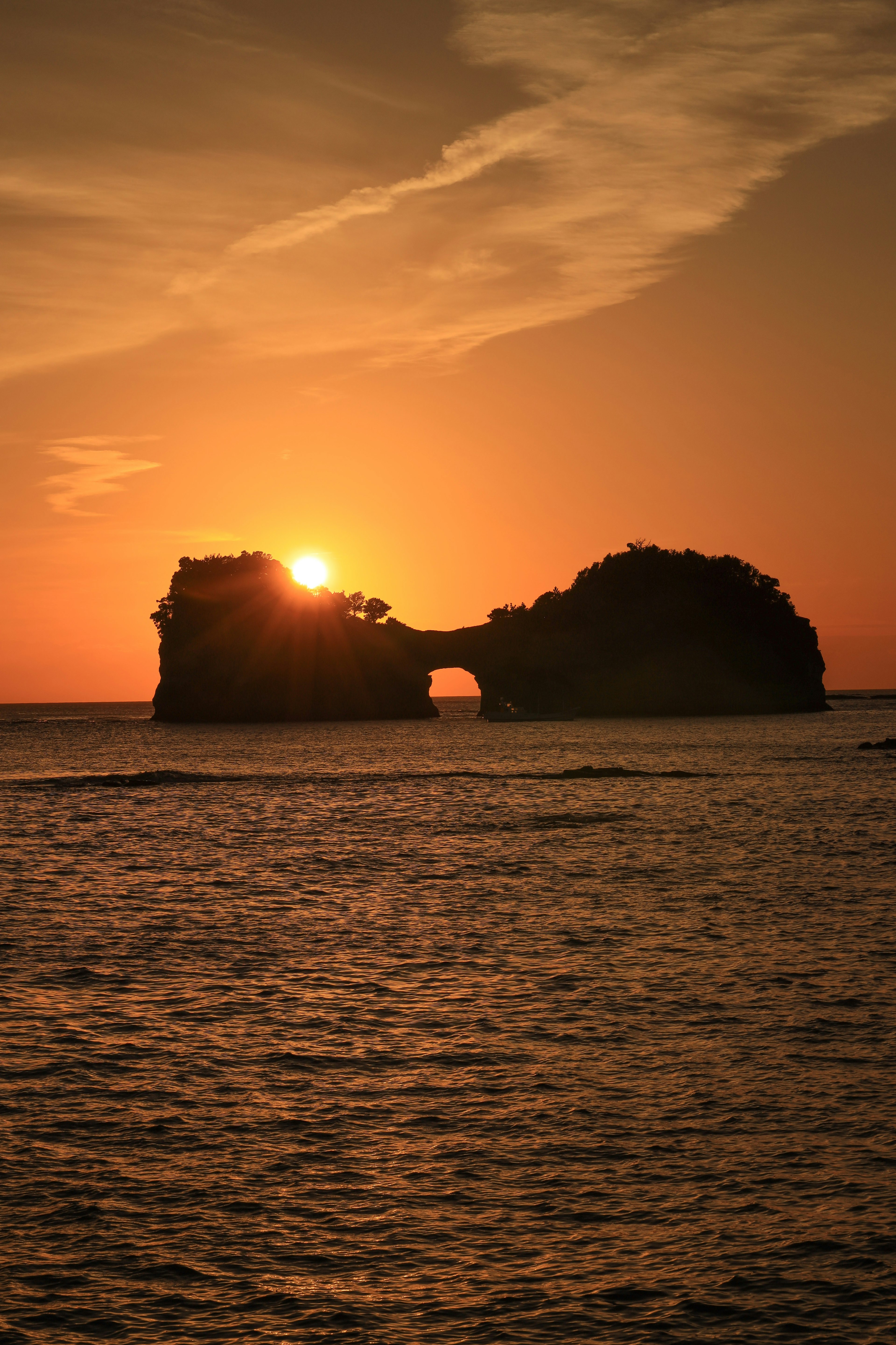 Isola con un arco silhouettato dal sole al tramonto sull'oceano