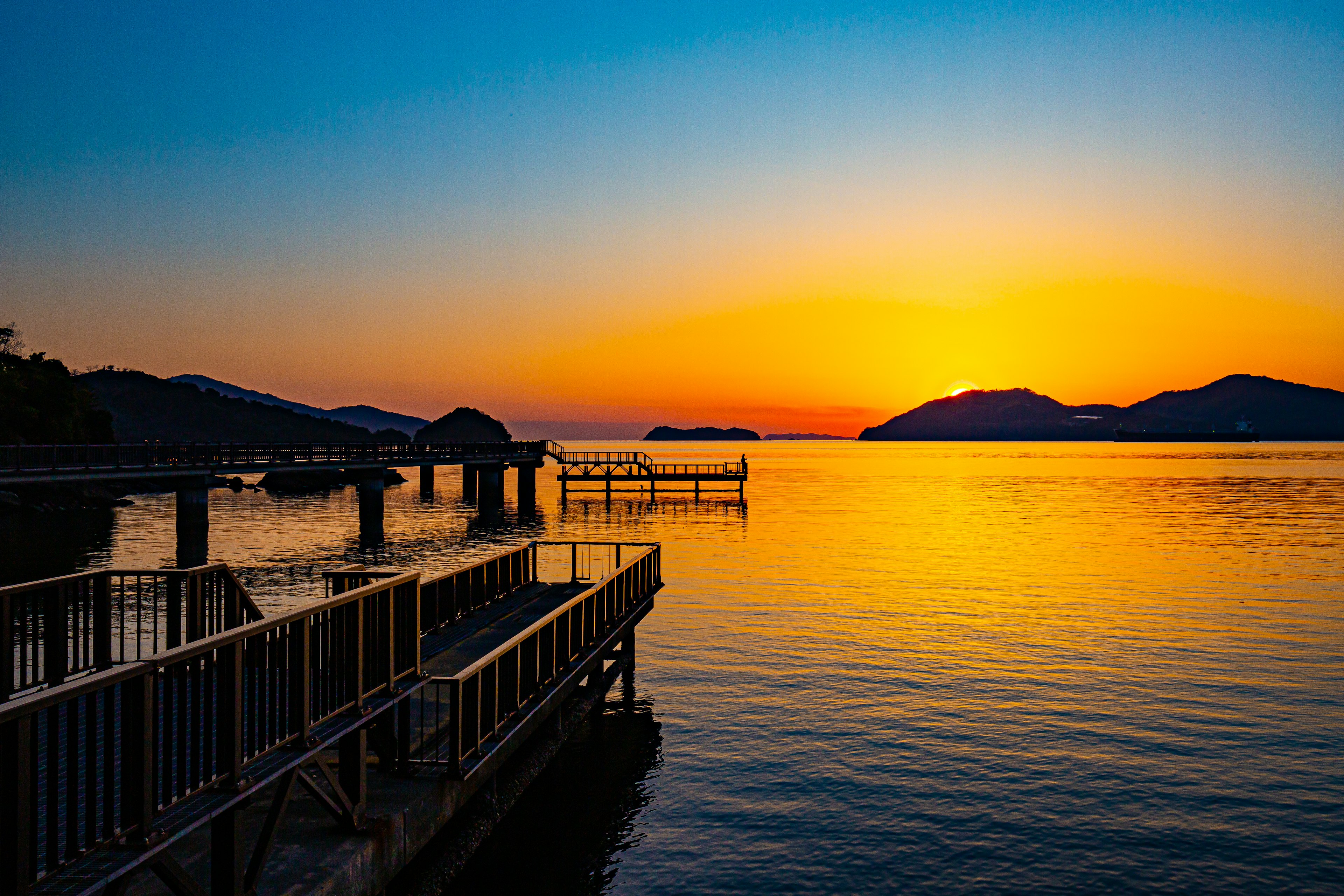 美しい夕焼けが水面に反射し、桟橋が静かに佇む風景