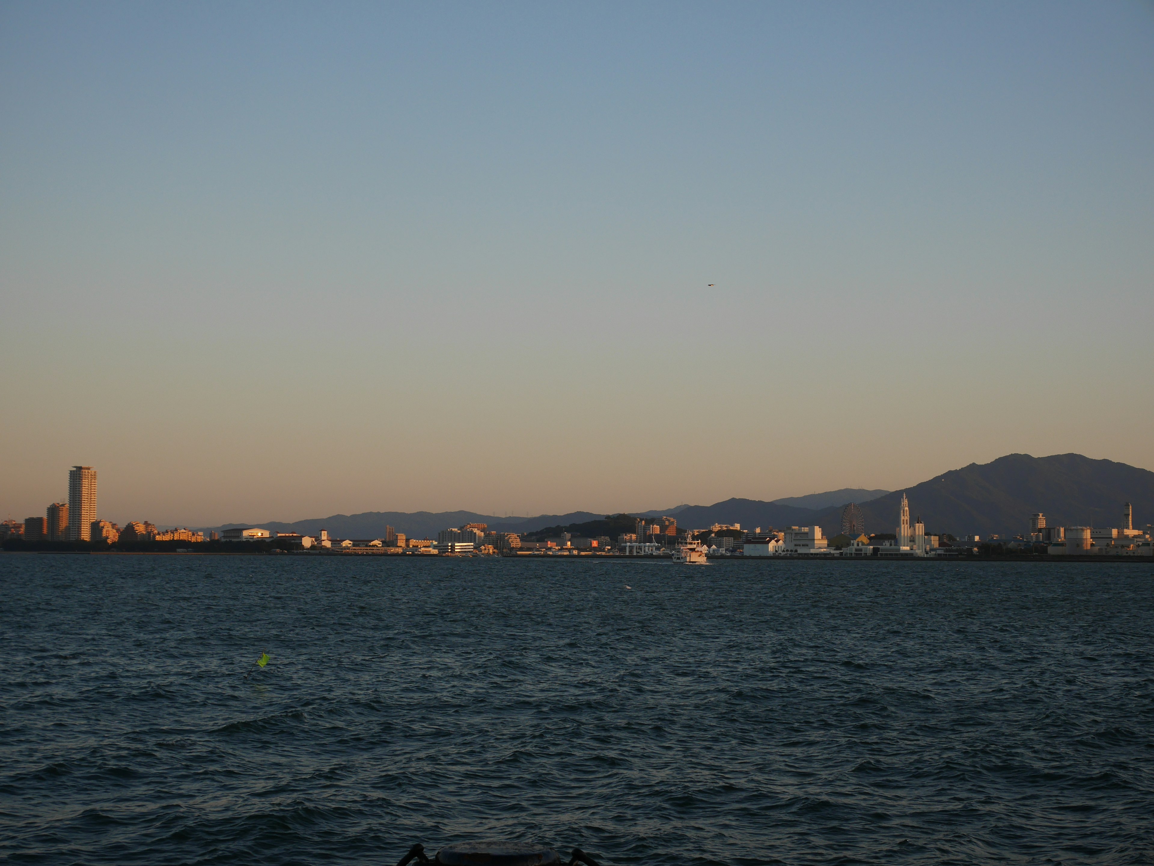 Ligne d'horizon de la ville au crépuscule avec de l'eau au premier plan