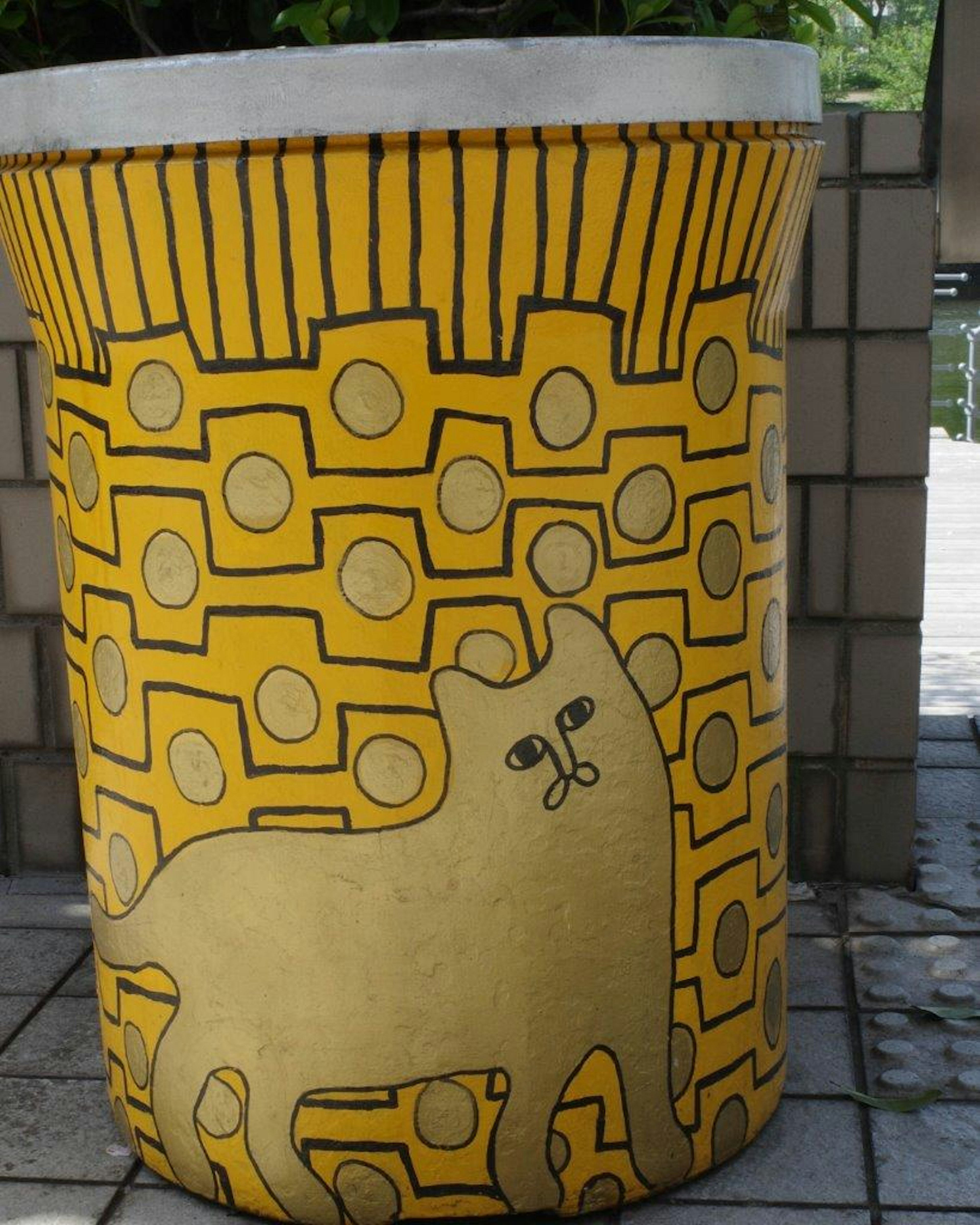 Objet cylindrique jaune avec une illustration de chat et des motifs géométriques