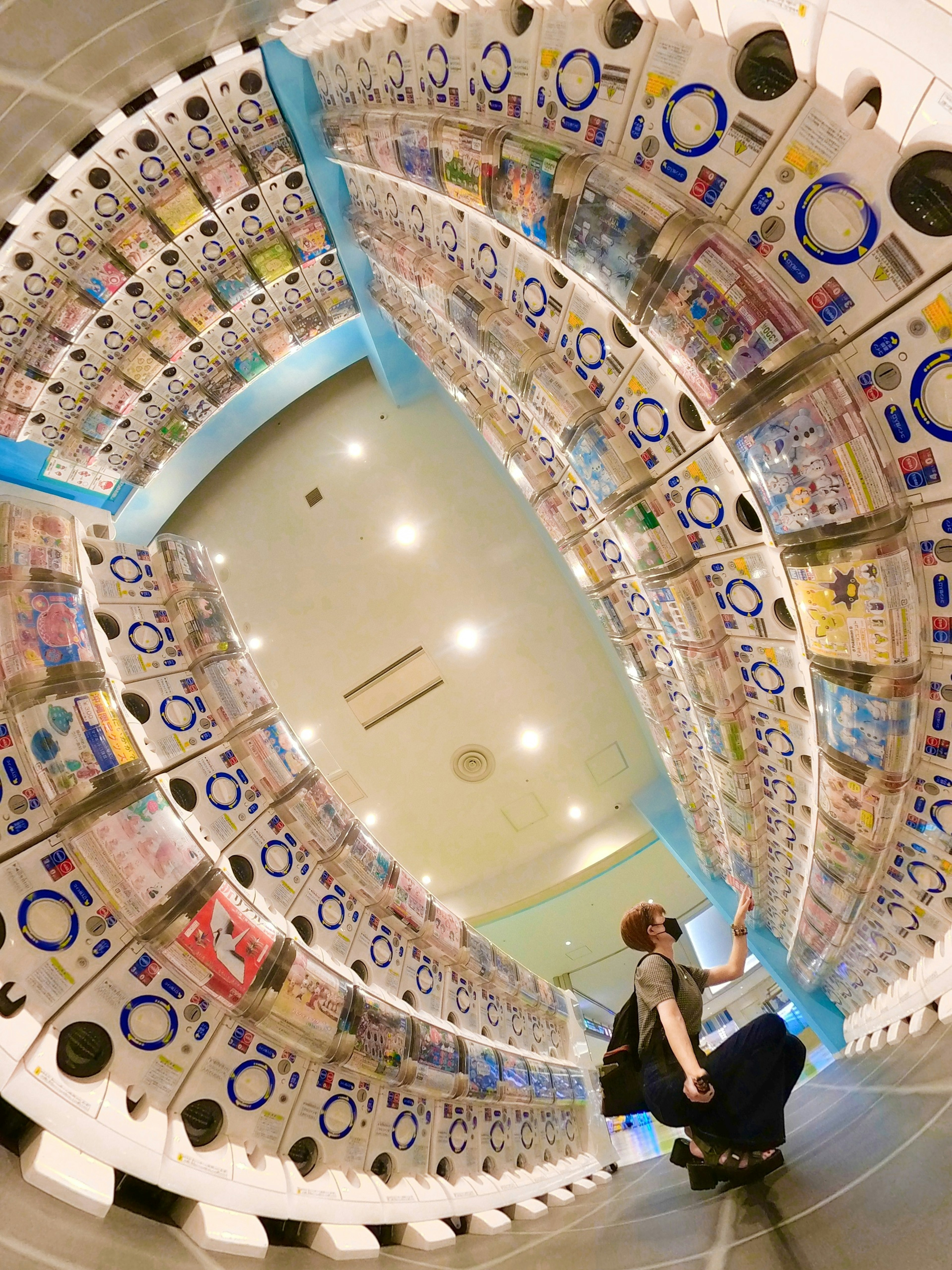 Interior of an arcade filled with colorful capsule toys and a person