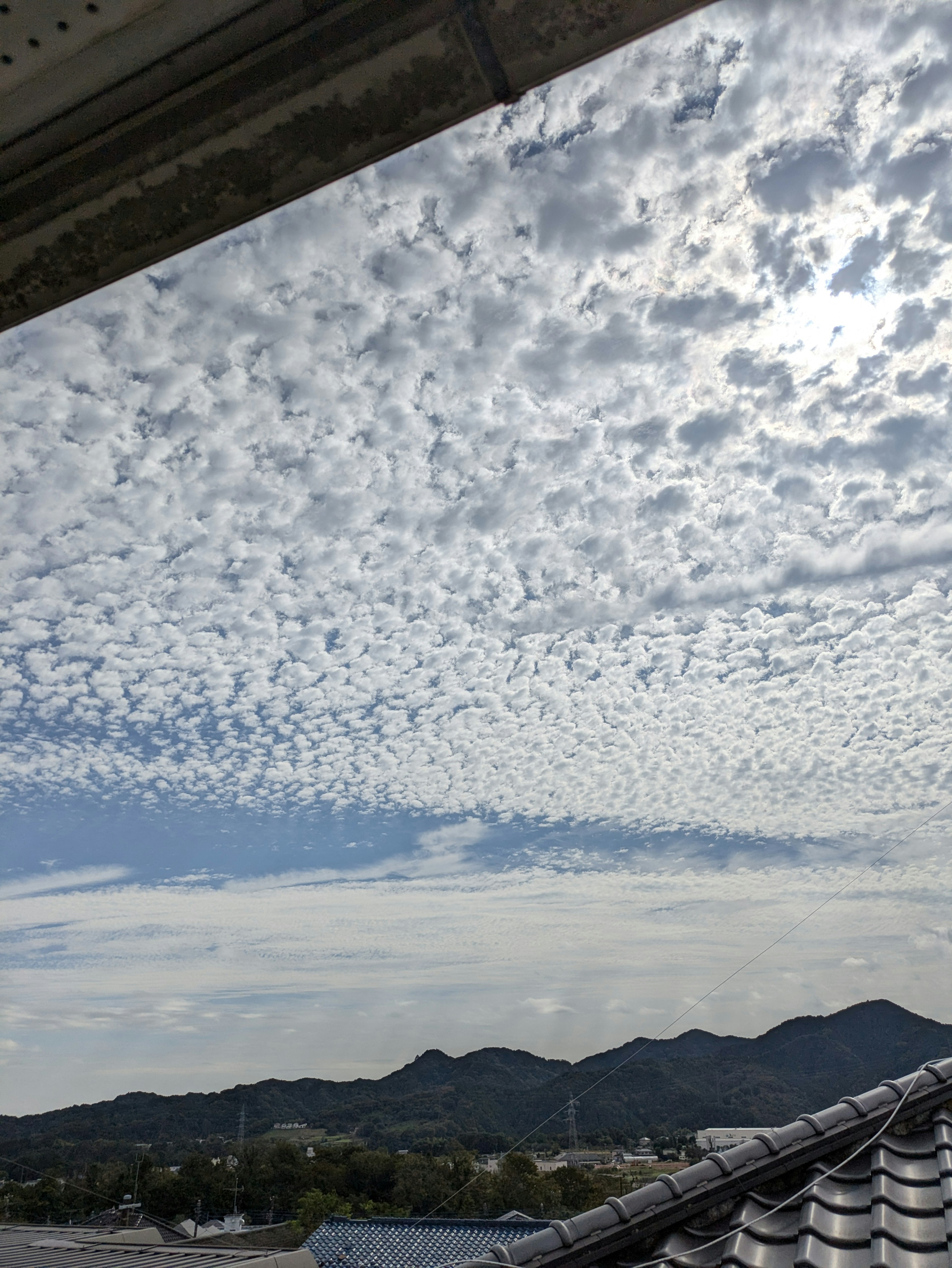 Patterned clouds in a blue sky with mountains in the background