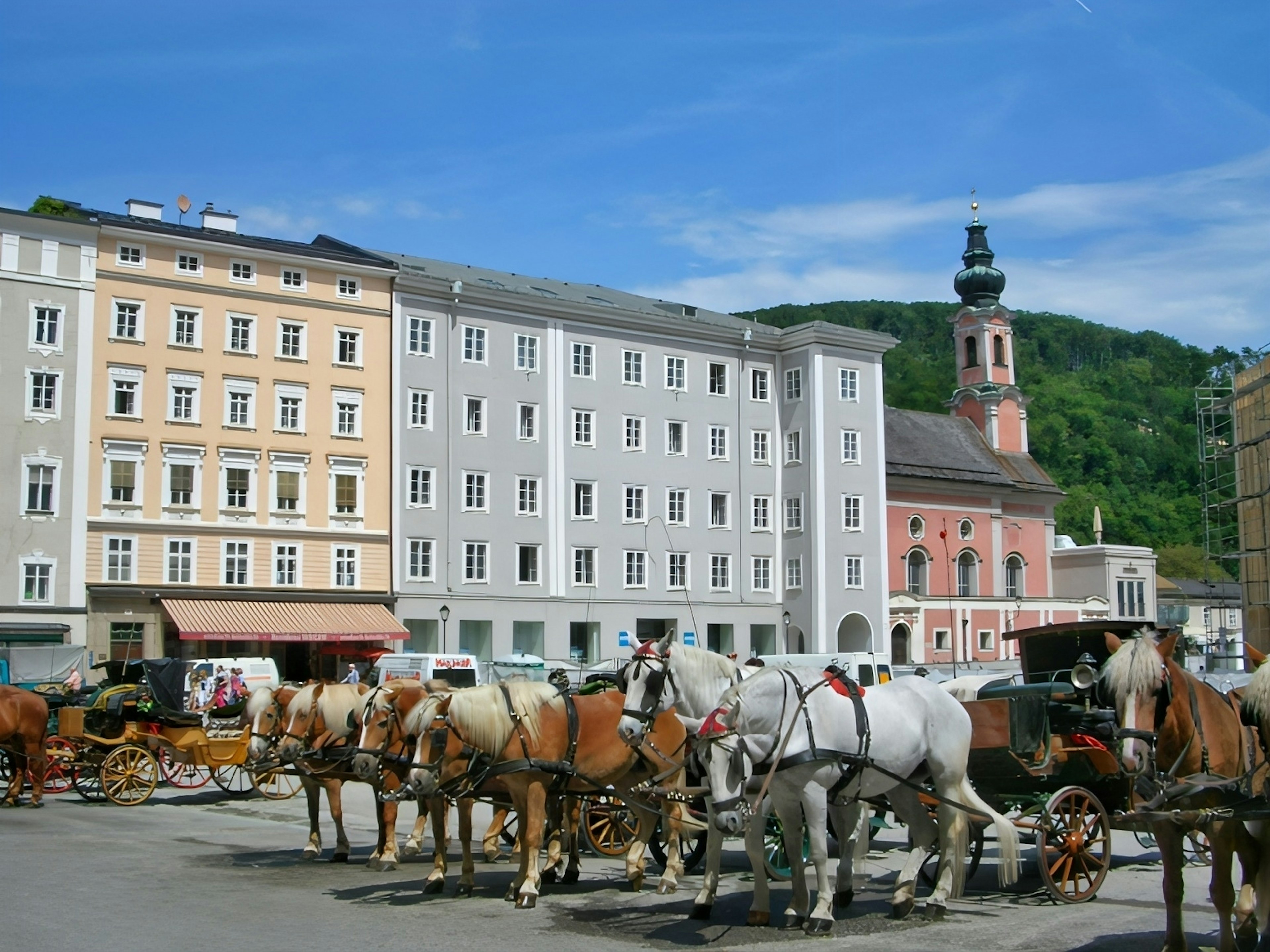 Historic square with horse-drawn carriages and colorful buildings