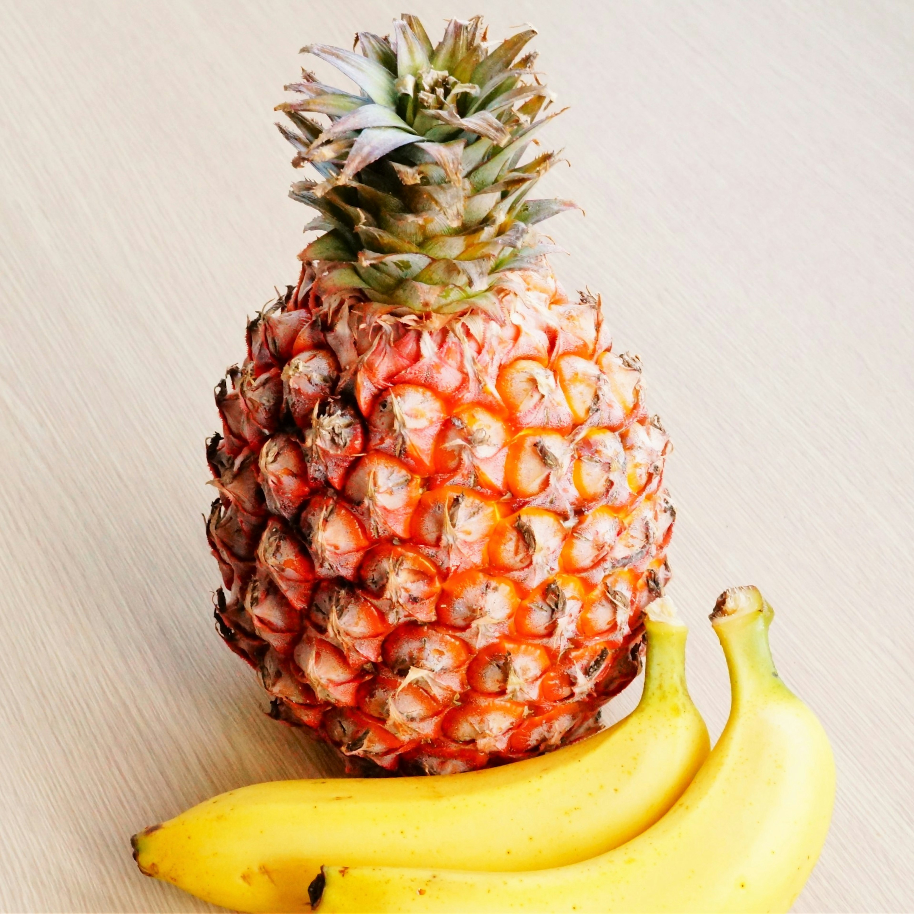 Ananas avec deux bananes sur une surface en bois clair